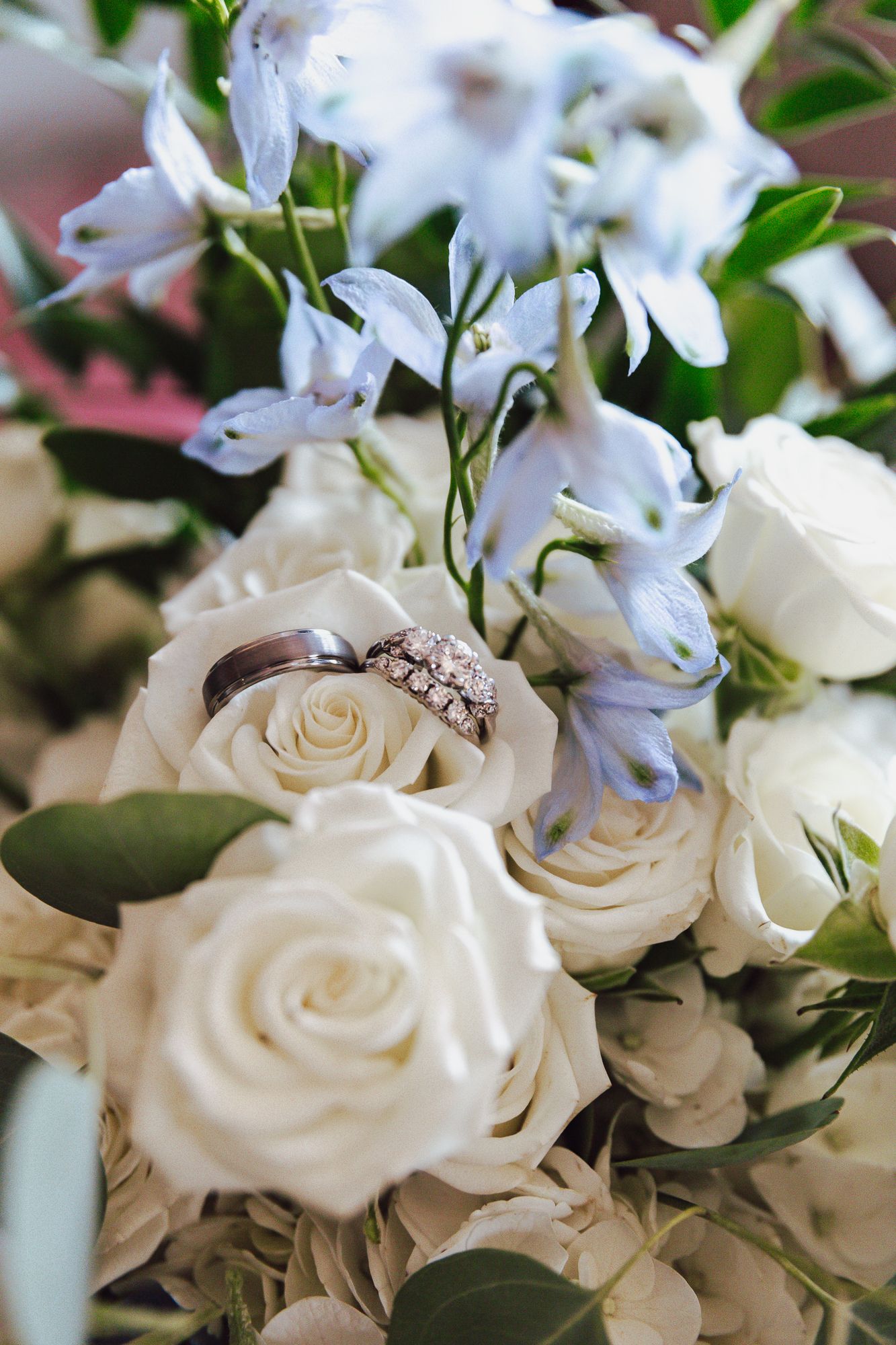 Elegant white roses and wedding ring arrangement with delicate floral details.