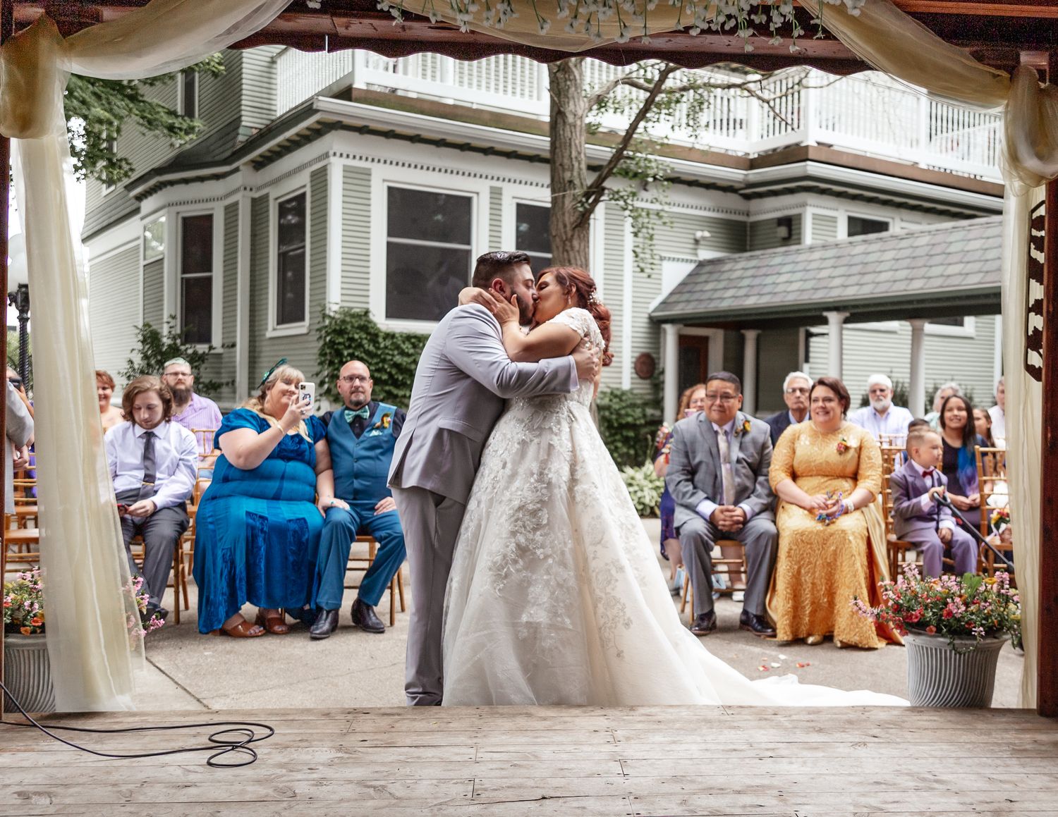 Wedding celebration scene on a classic porch with guests seated in the background.