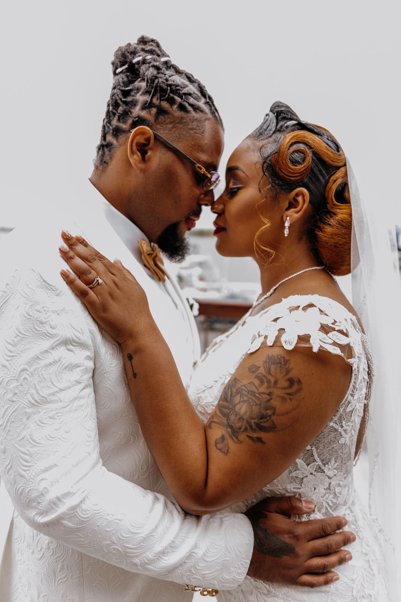 Stylish wedding couple in white sharing tender embrace in artistic portrait.