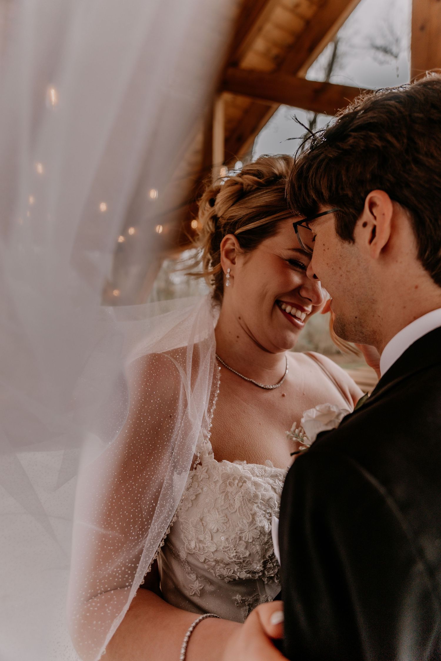 Tender moment between newlyweds under soft lighting at indoor venue.