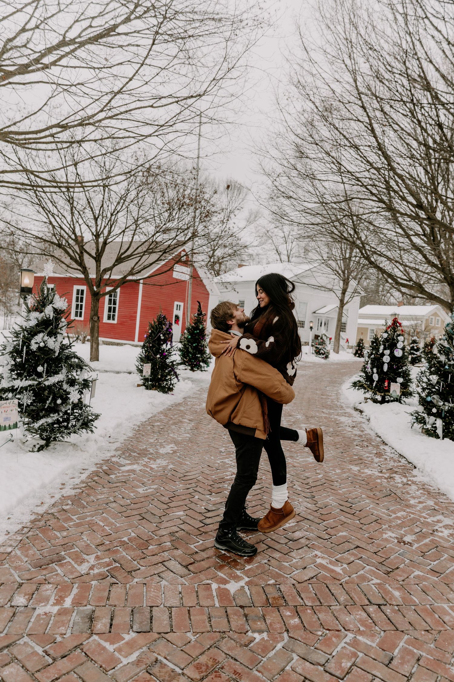 A playful winter scene on a brick walkway with snow-covered buildings and bare trees in the background.