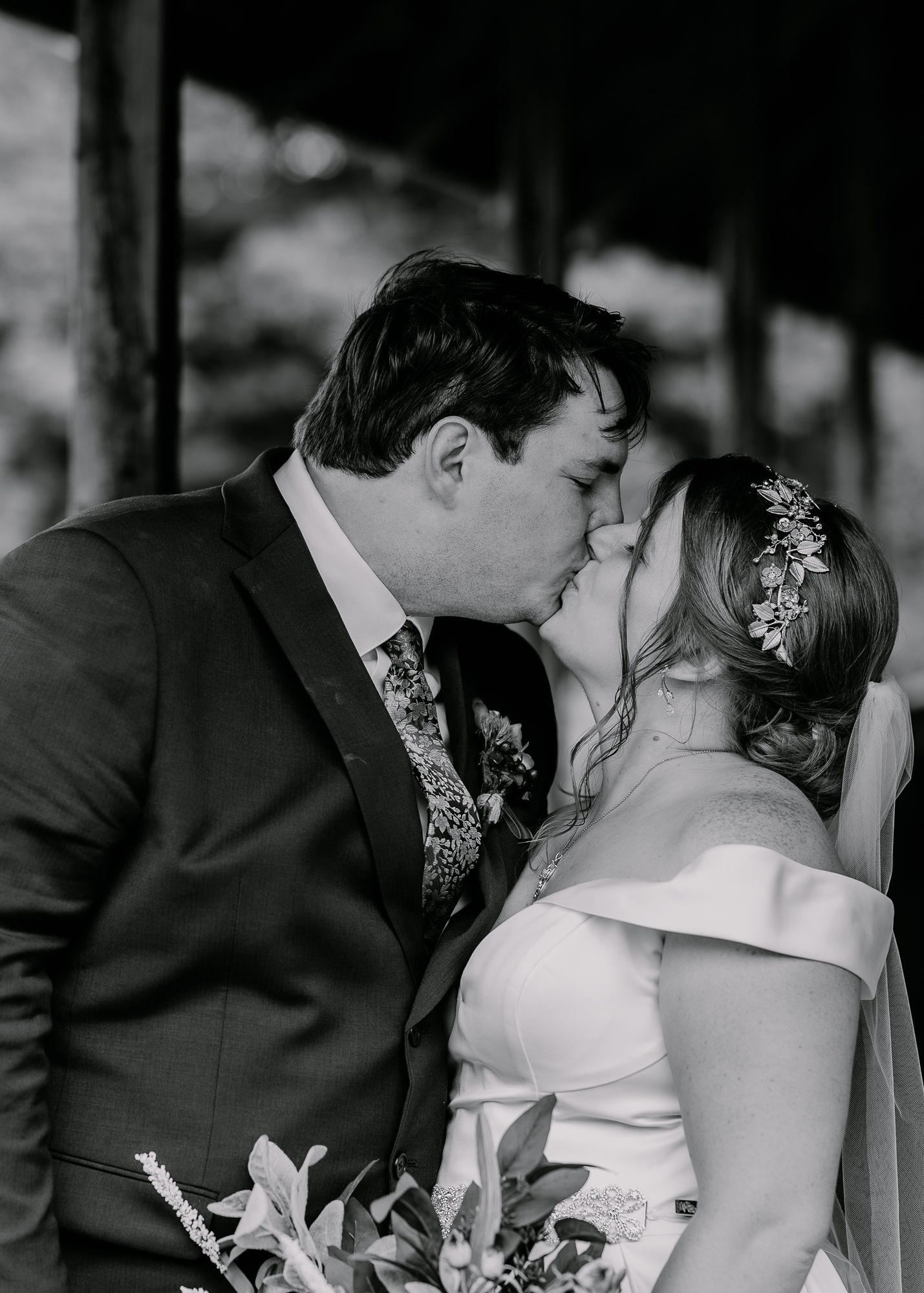 A romantic black and white portrait of newlyweds sharing their first kiss.