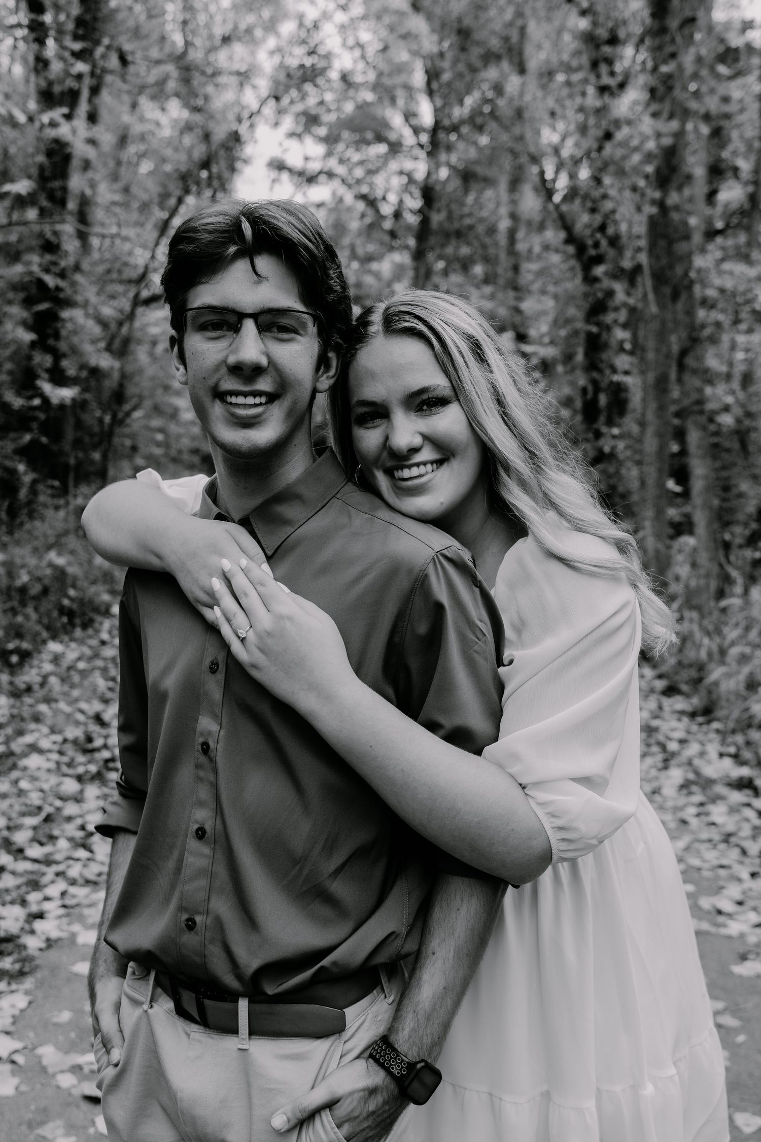 Black and white portrait of couple embracing during forest engagement session.