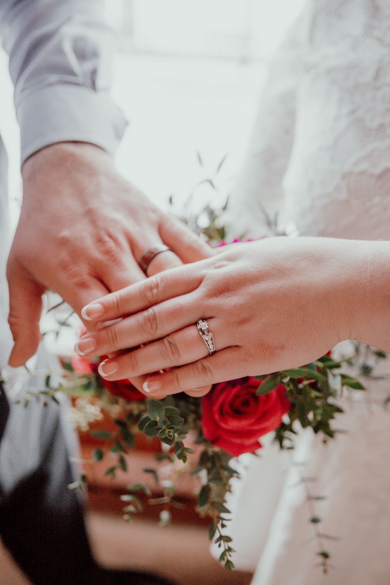 Close-up photos of wedding rings and hands with red rose bouquet details.