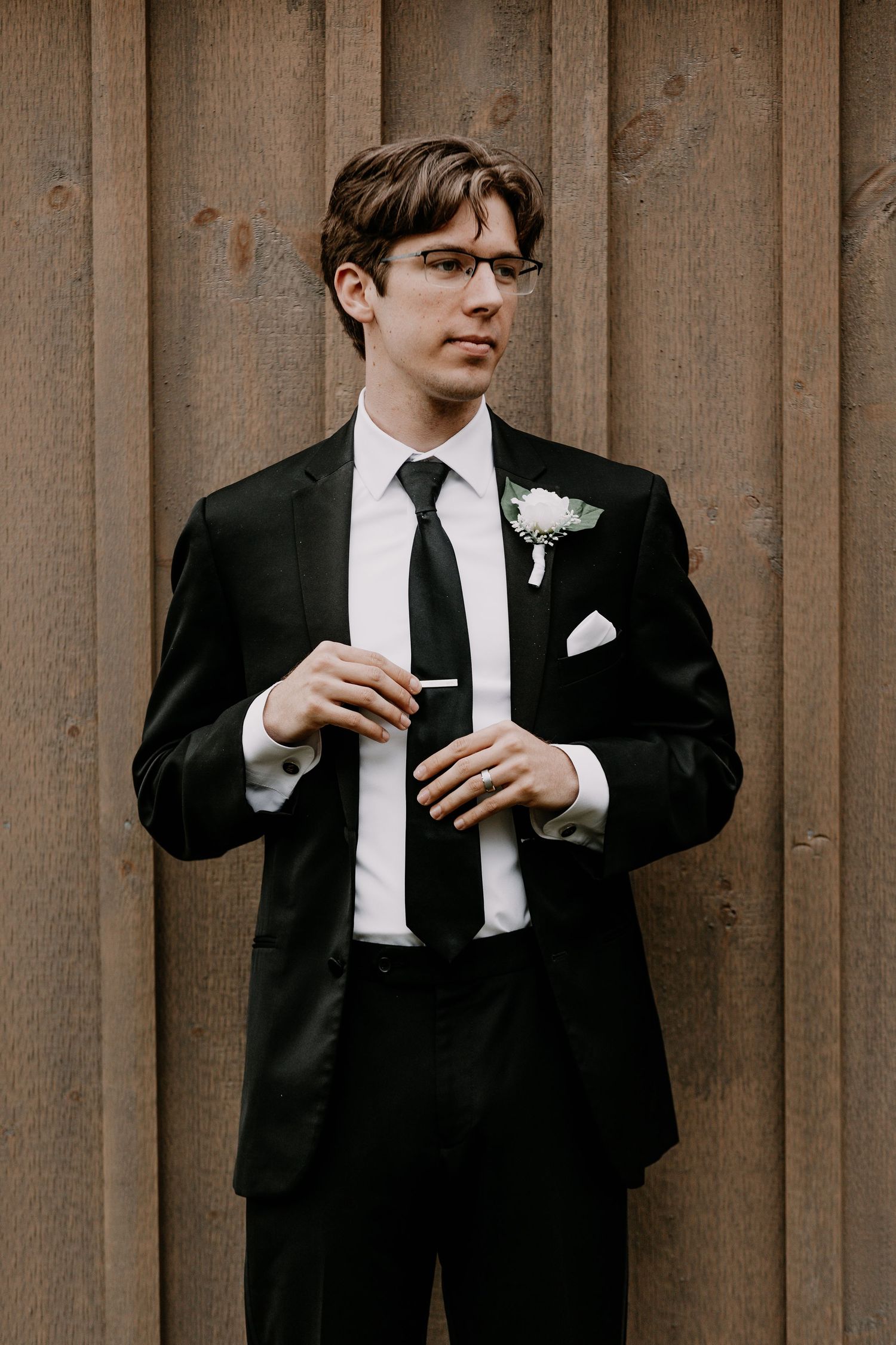 Wedding attire details showing black suit, white pocket square, and boutonniere.