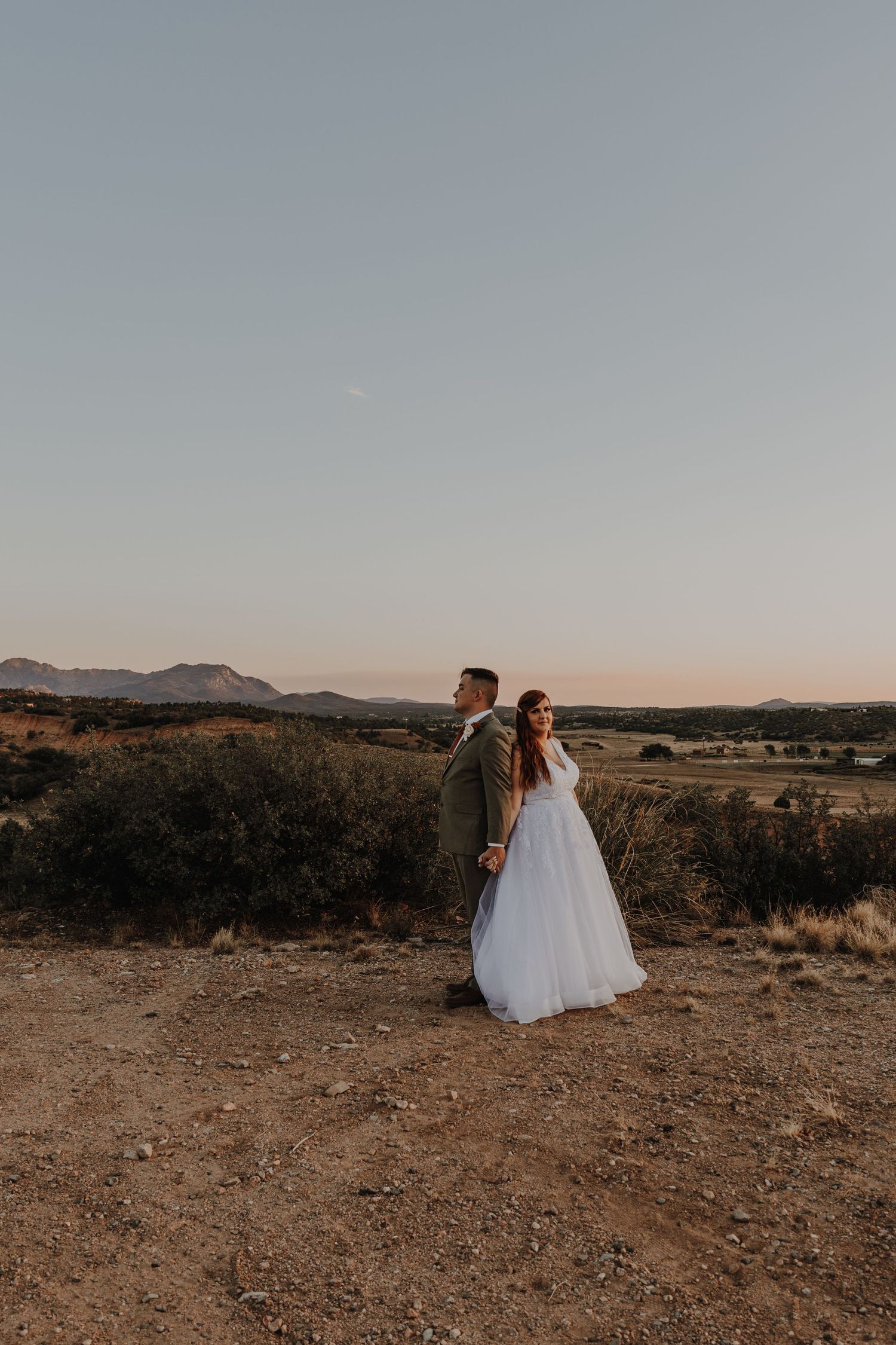 Wide landscape shot of newlyweds in a vast desert setting during dusk.