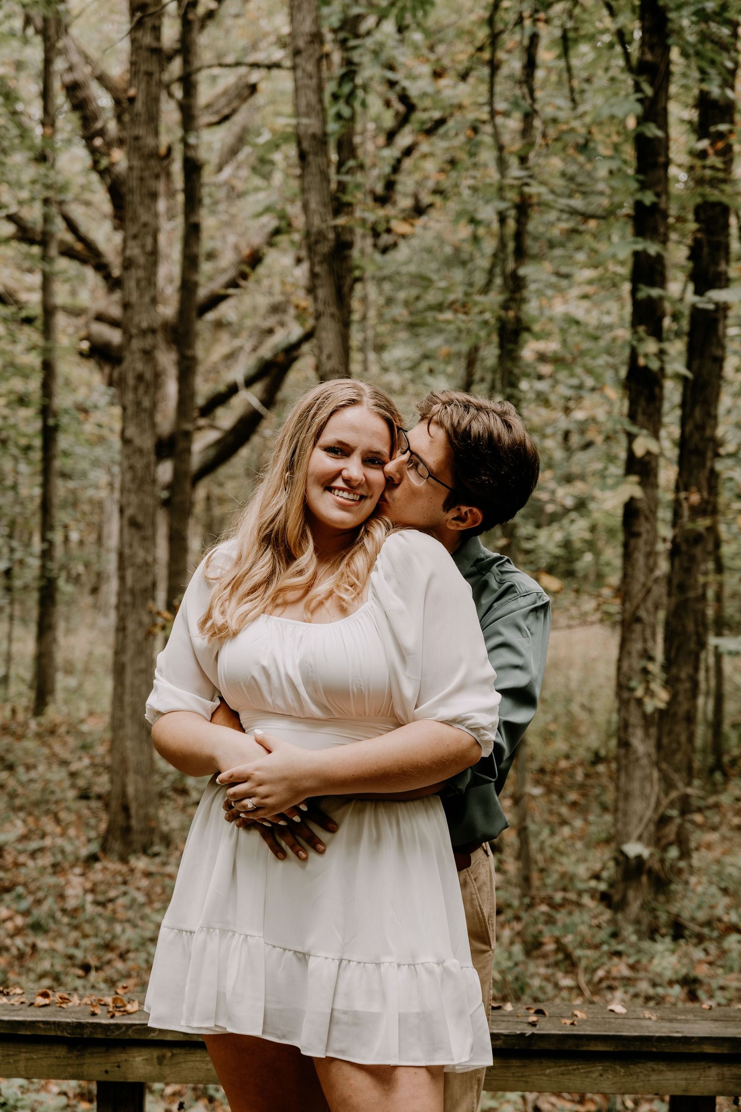 Loving couple sharing intimate moment on wooden deck in forest setting.
