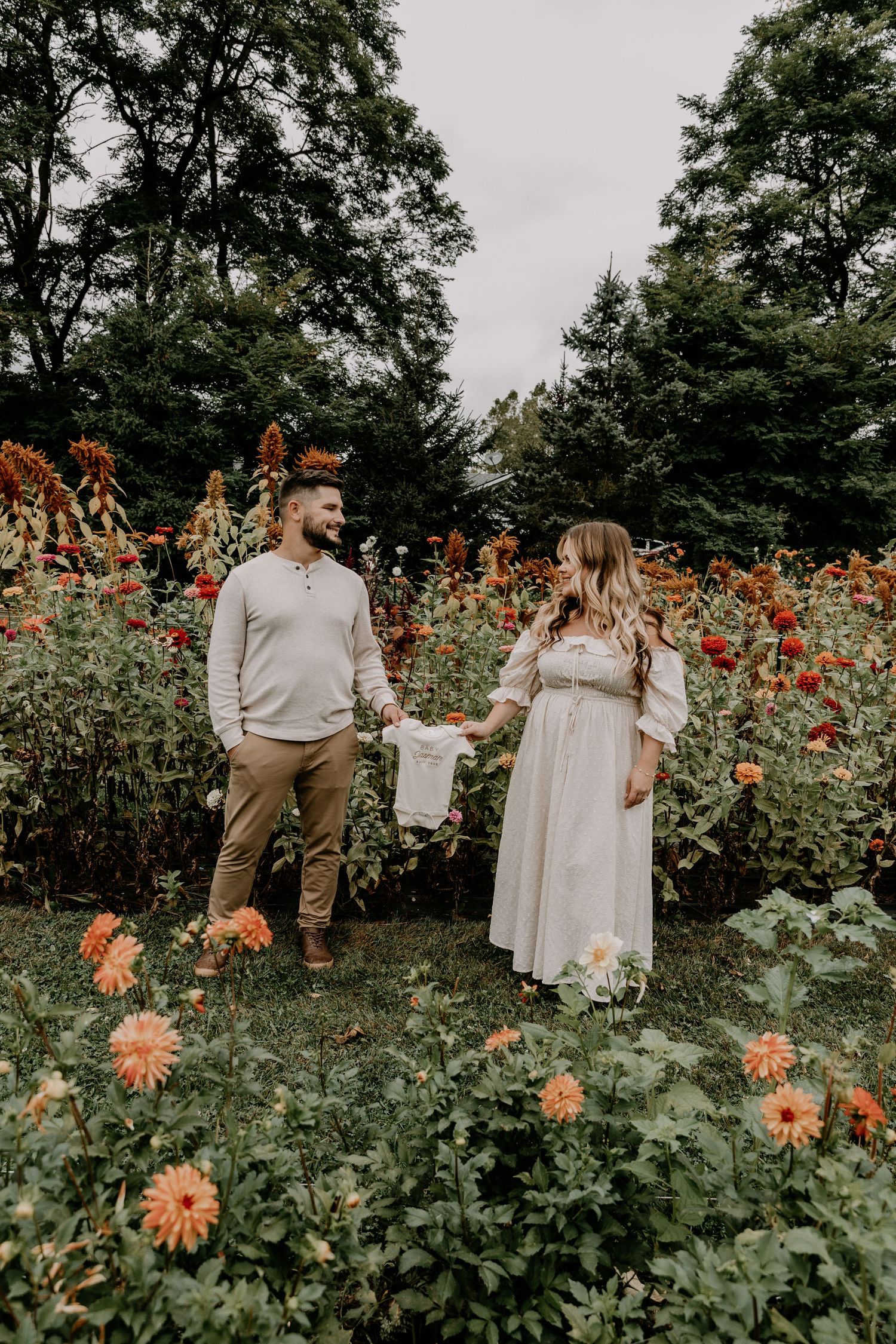 Joyful outdoor photography session in a vibrant garden with orange dahlias.