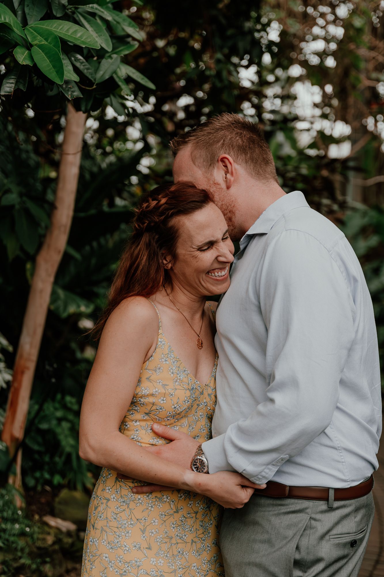 A joyful couple sharing a candid moment among tropical plants.