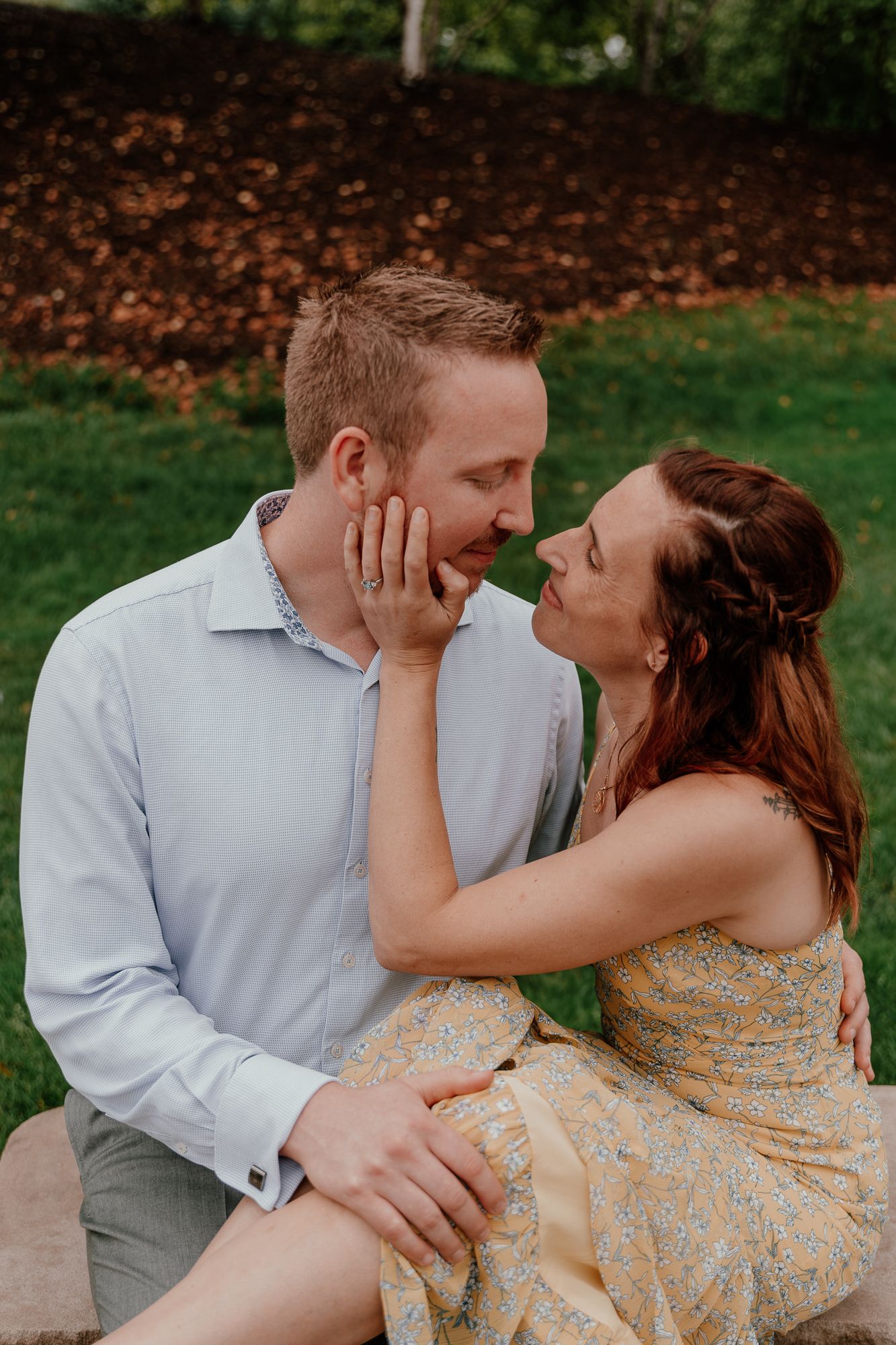 A candid moment between an engaged couple sharing an intimate moment outdoors.