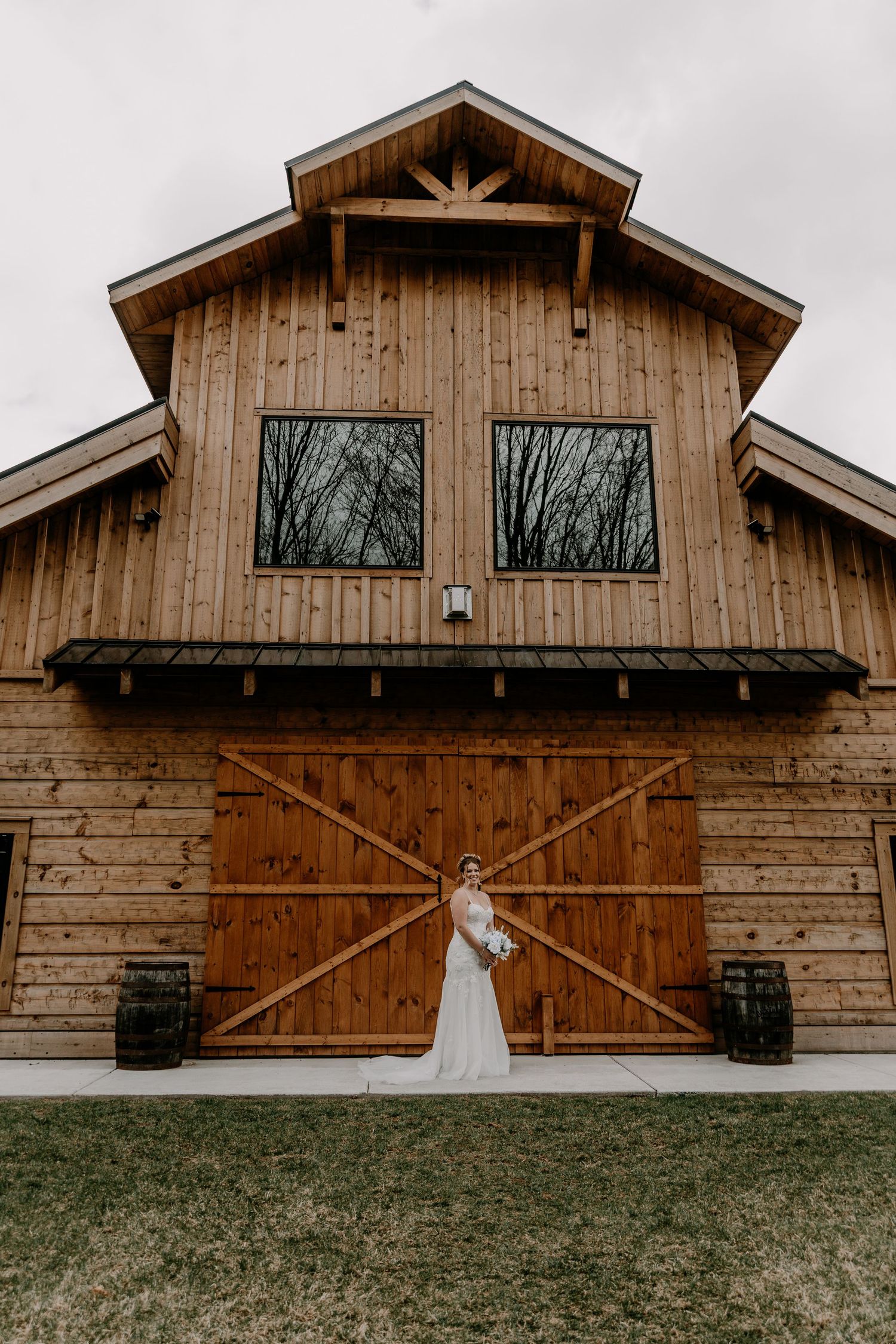 Exterior view of a rustic wooden barn wedding venue with large windows and natural wood siding.