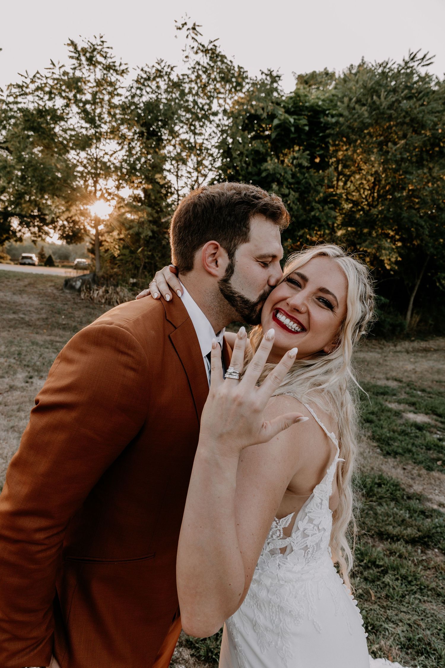 A joyful wedding moment captured during golden hour with trees and natural lighting in the background.