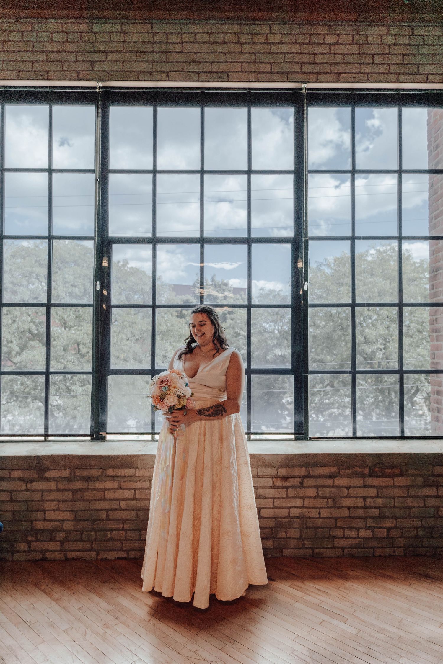Modern brick and glass venue interior with wedding dress displayed in natural light.