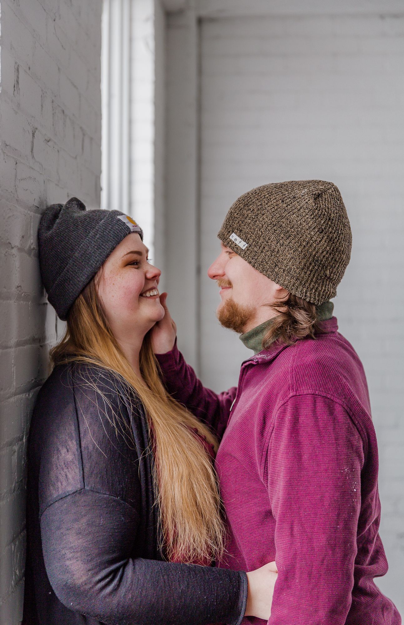 Winter photoshoot showing playful interactions between two people wearing knit beanies.