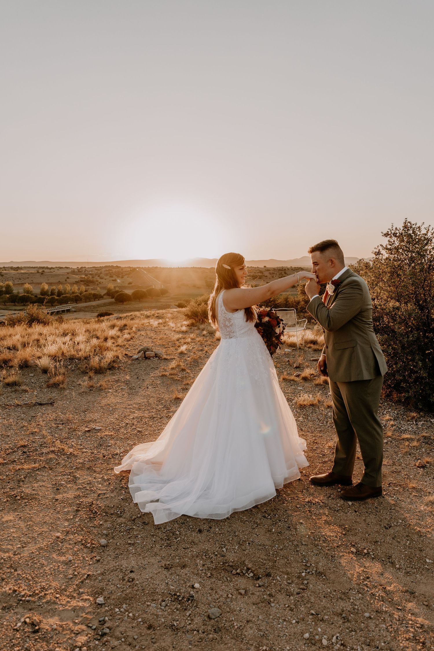 Wedding couple dancing and twirling in a desert setting during golden hour.