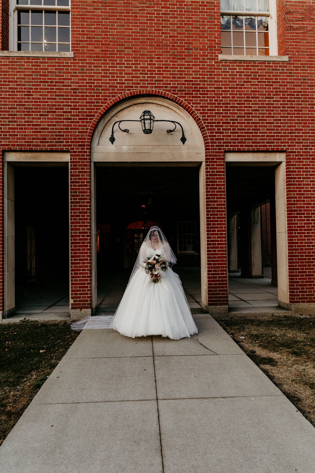 Dramatic wedding dress photos against red brick building exterior.