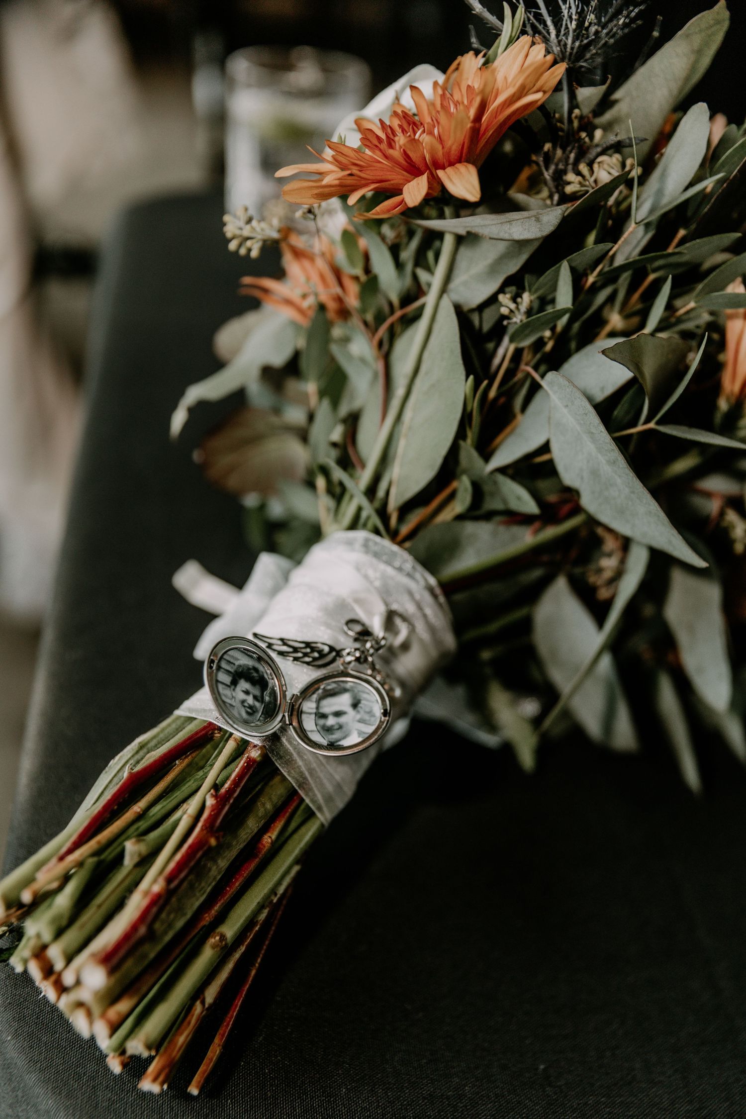 A bridal bouquet with coral-colored flowers and eucalyptus wrapped in a vintage brooch detail.
