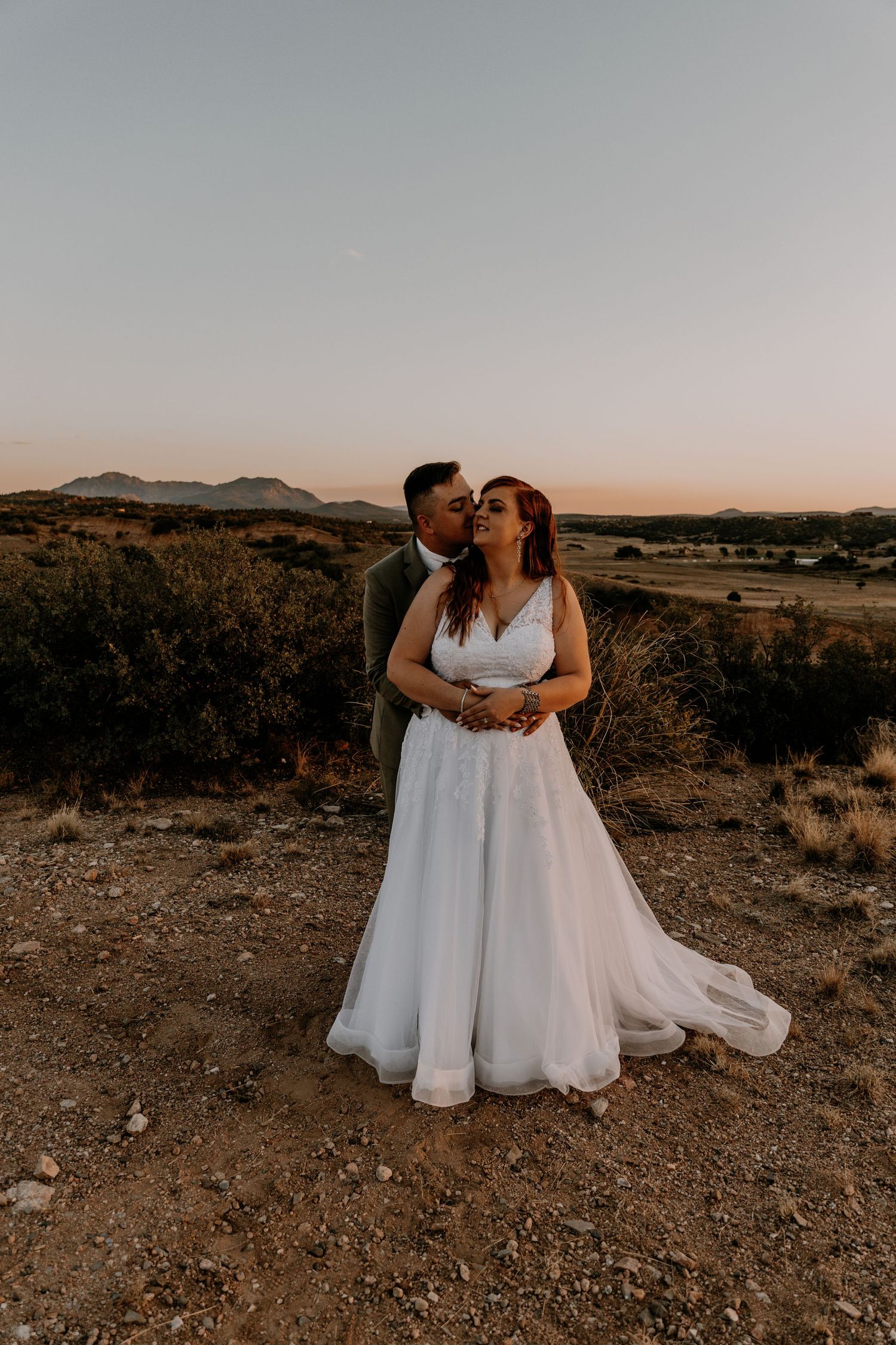 Couple sharing intimate moment during sunset desert wedding photoshoot.