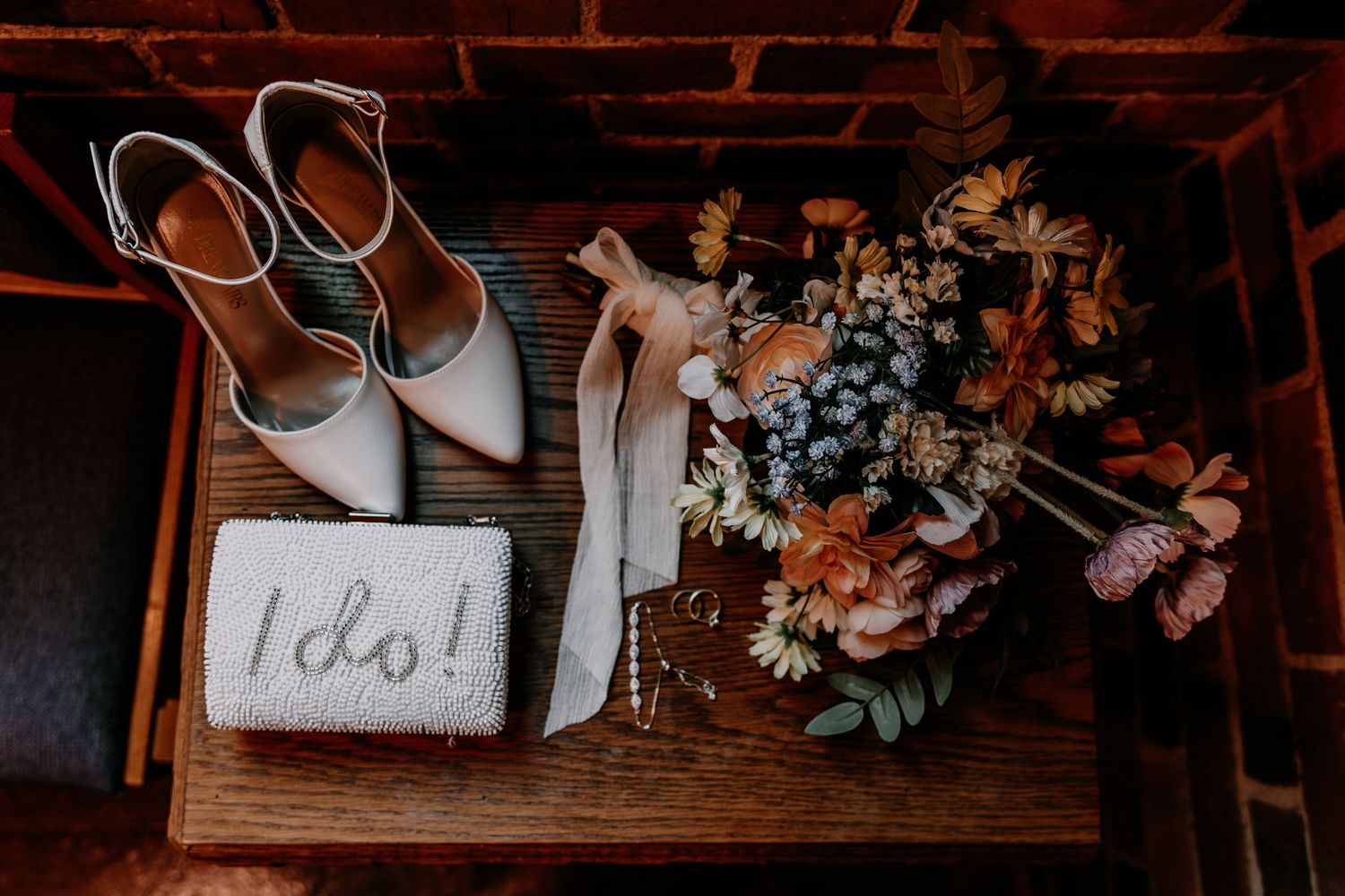 Wedding details including floral arrangements, rings, invitations, and rustic wooden decor against brick wall backgrounds.