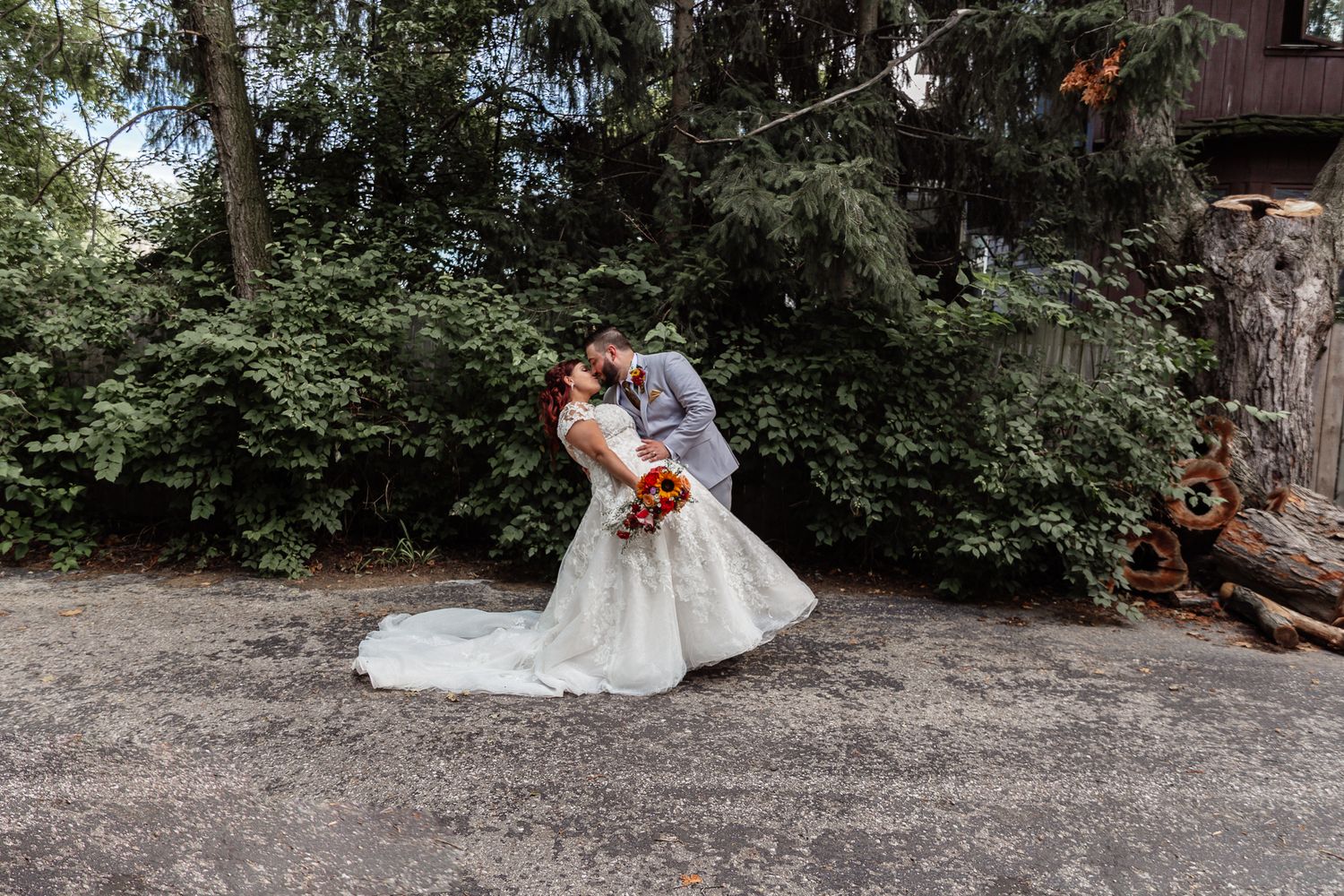 A romantic wedding photoshoot set against a wooded backdrop with the couple's gowns trailing on natural ground.