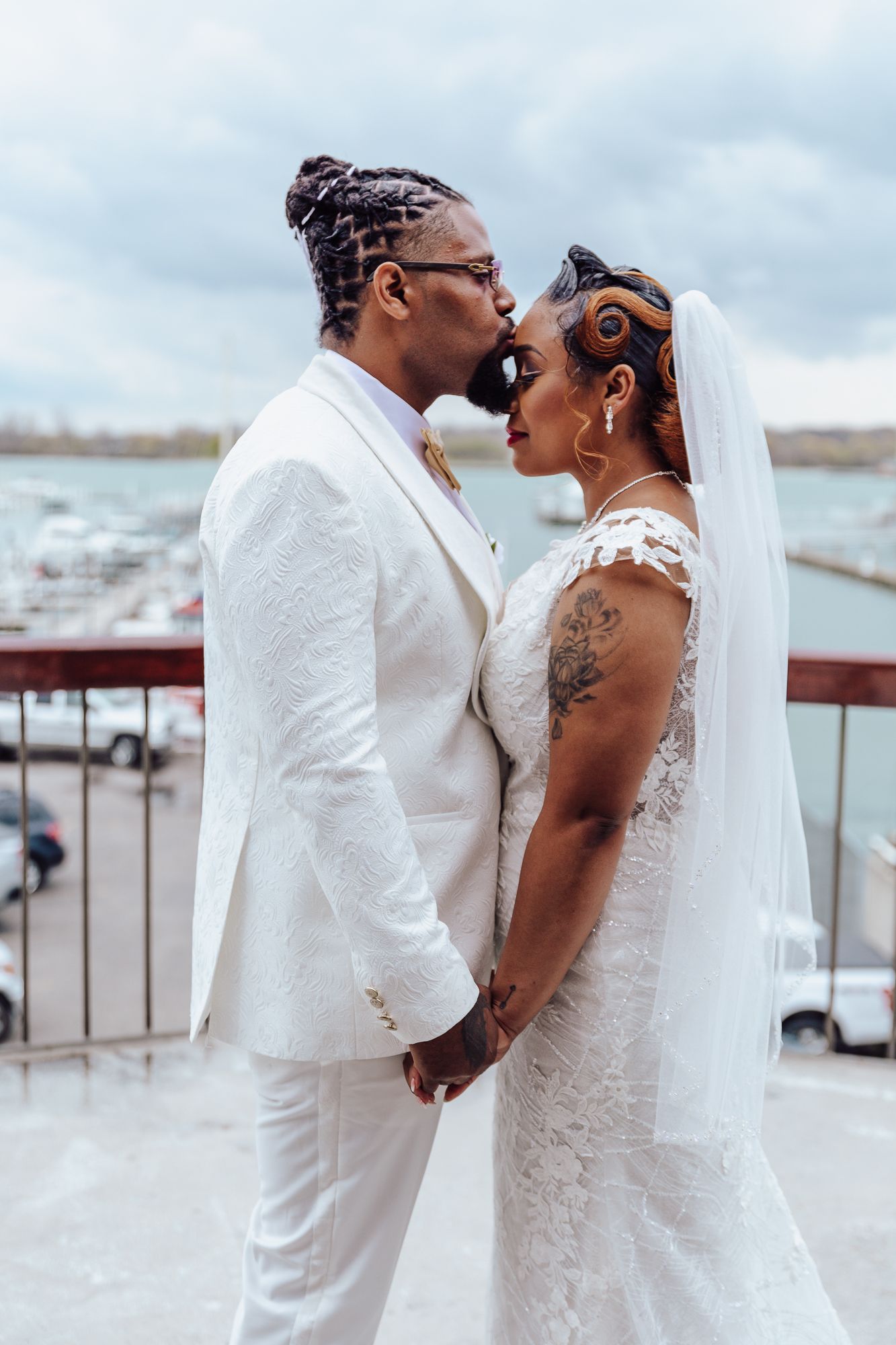 Intimate portrait of wedding couple against cloudy marina backdrop.