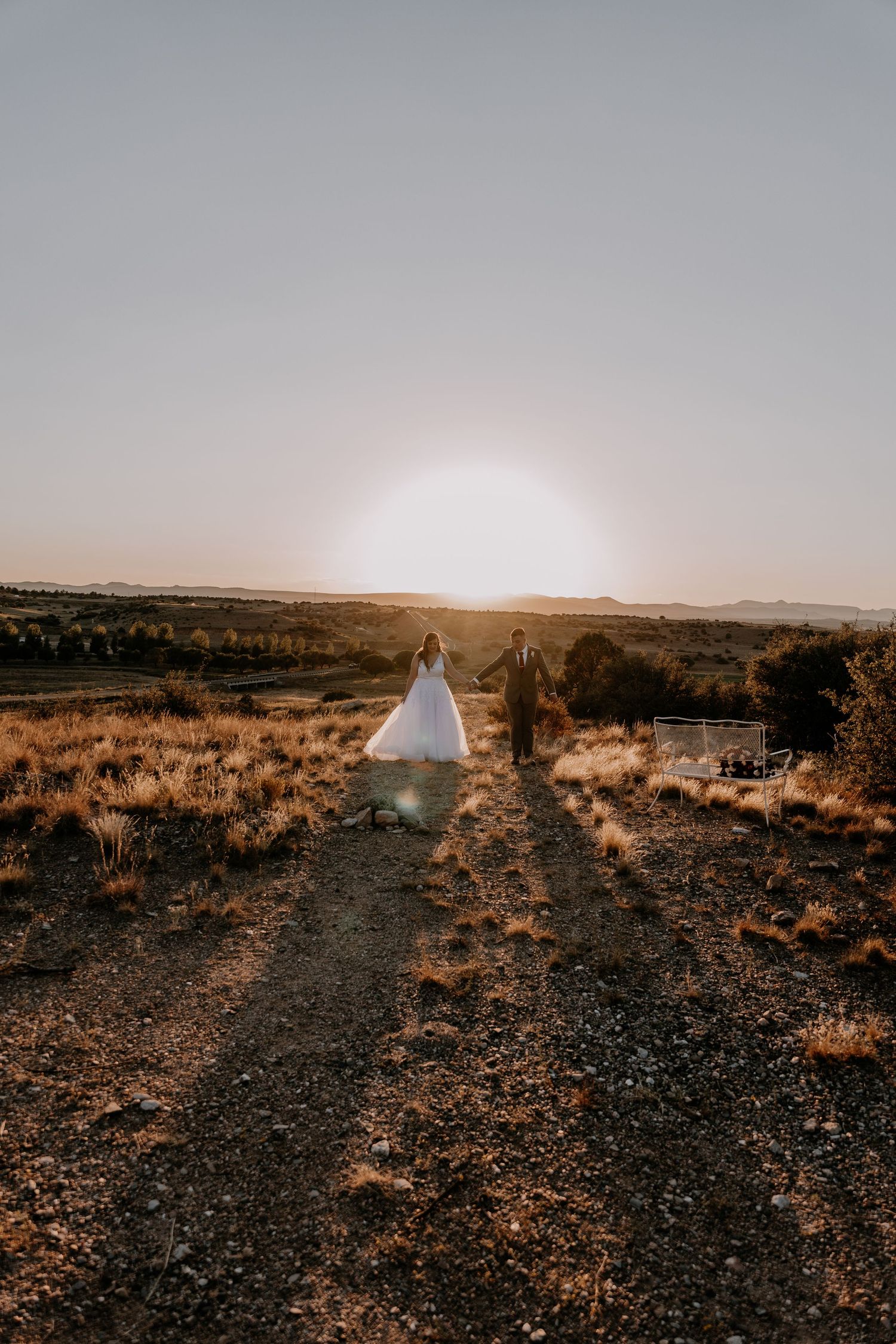 A scenic desert landscape at sunset with a white dress silhouette on a rocky path.