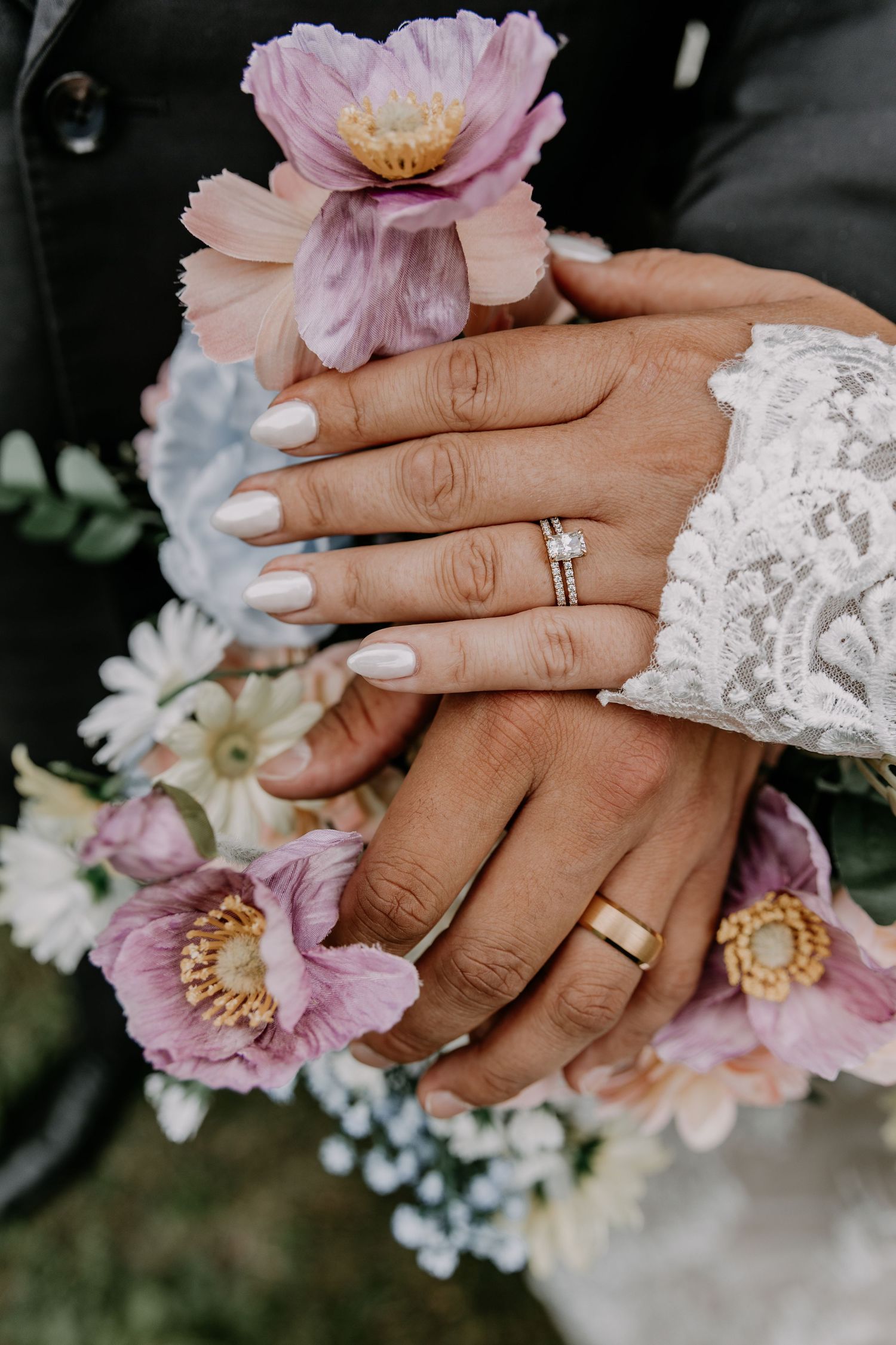 Close-up shots of wedding rings and hands with delicate pink flowers and lace details against a dark background.