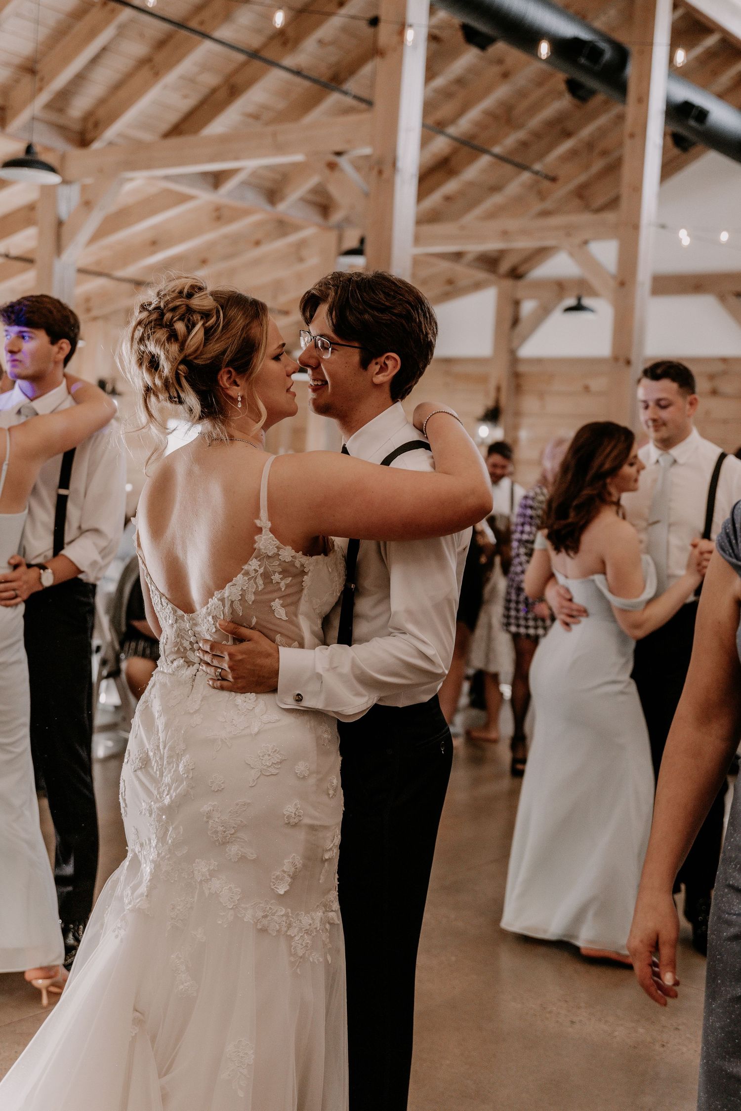 Couple shares intimate dance moment during wedding reception in rustic barn venue.