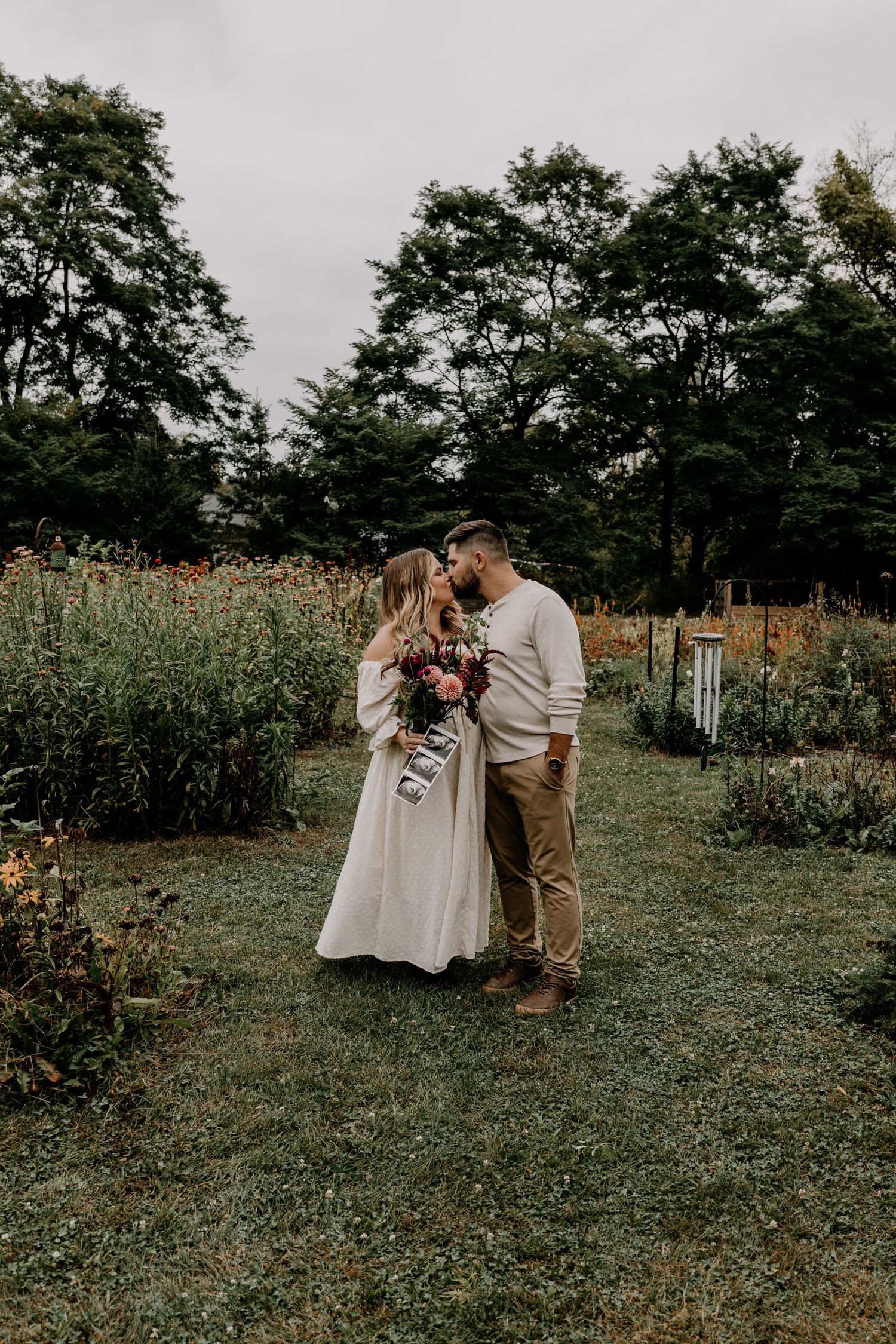 A couple shares an intimate moment in a serene garden landscape.
