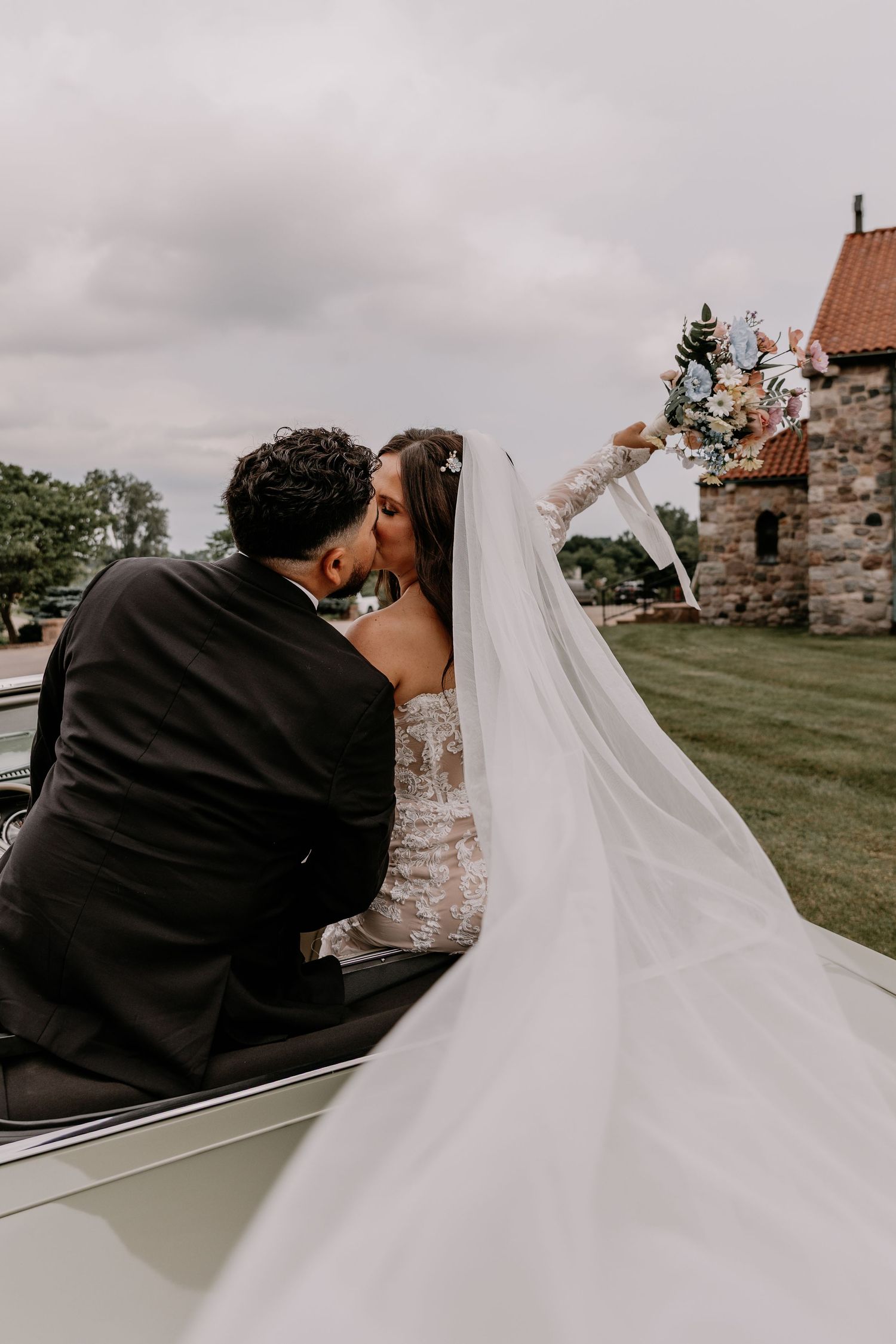 Back view of a newlywed couple embracing during their wedding ceremony at a rustic stone castle venue.