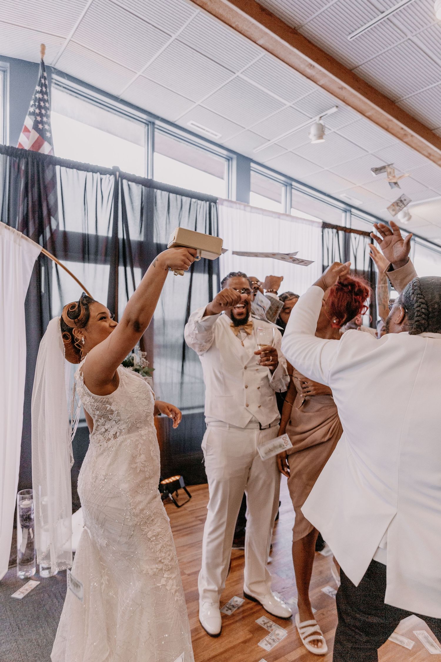 Wedding celebration with guests dancing and raising hands in an indoor venue.