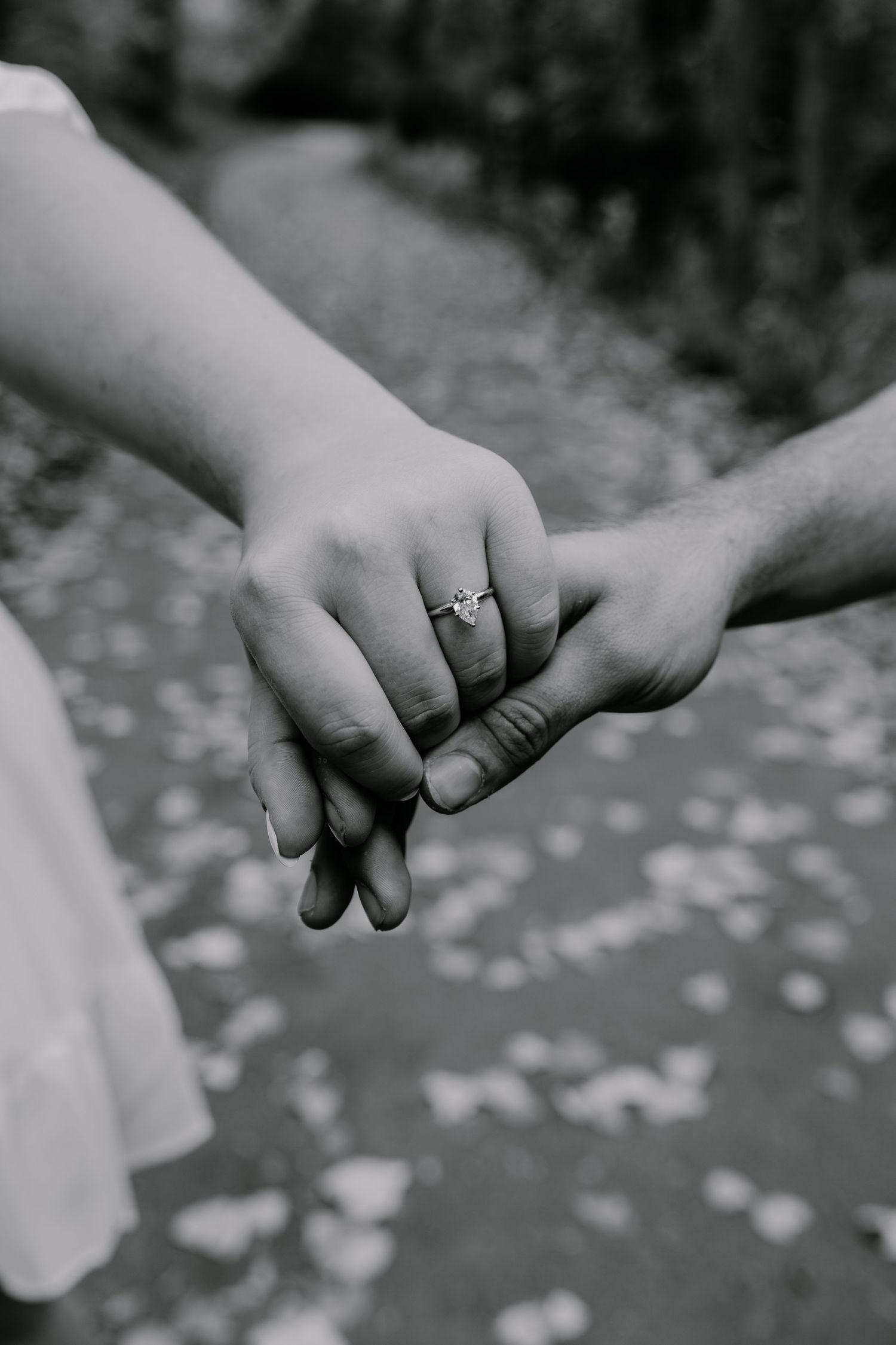Close-up shot of two hands clasped together with an engagement ring visible.