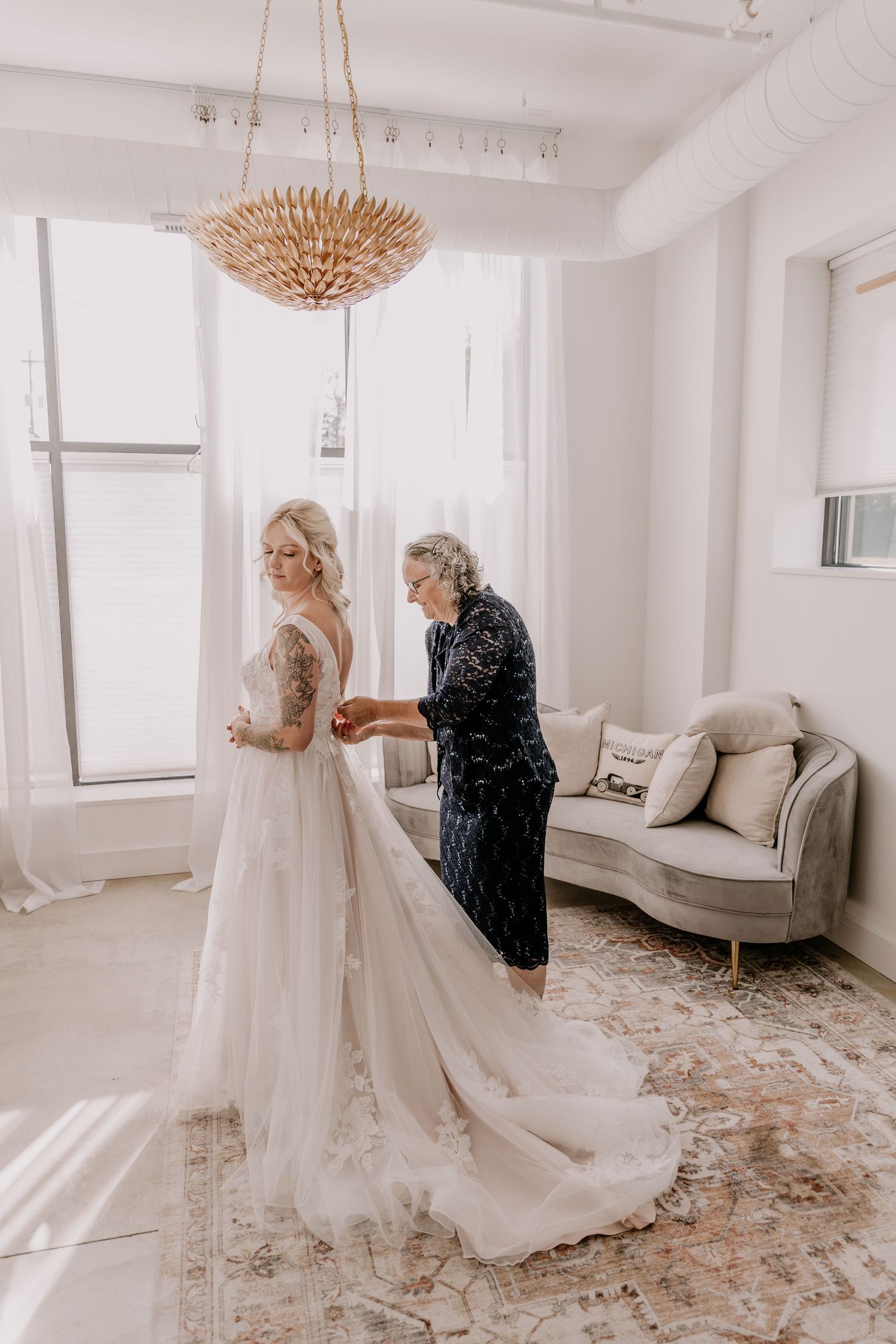 A beautiful wedding dress preparation scene in an elegant white room with rose gold accents and scattered petals on the floor.