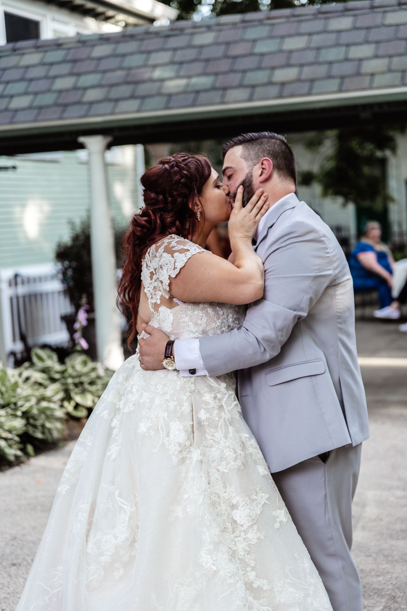 Tender wedding moment captured outside a house with grey and white attire creating a classic look.
