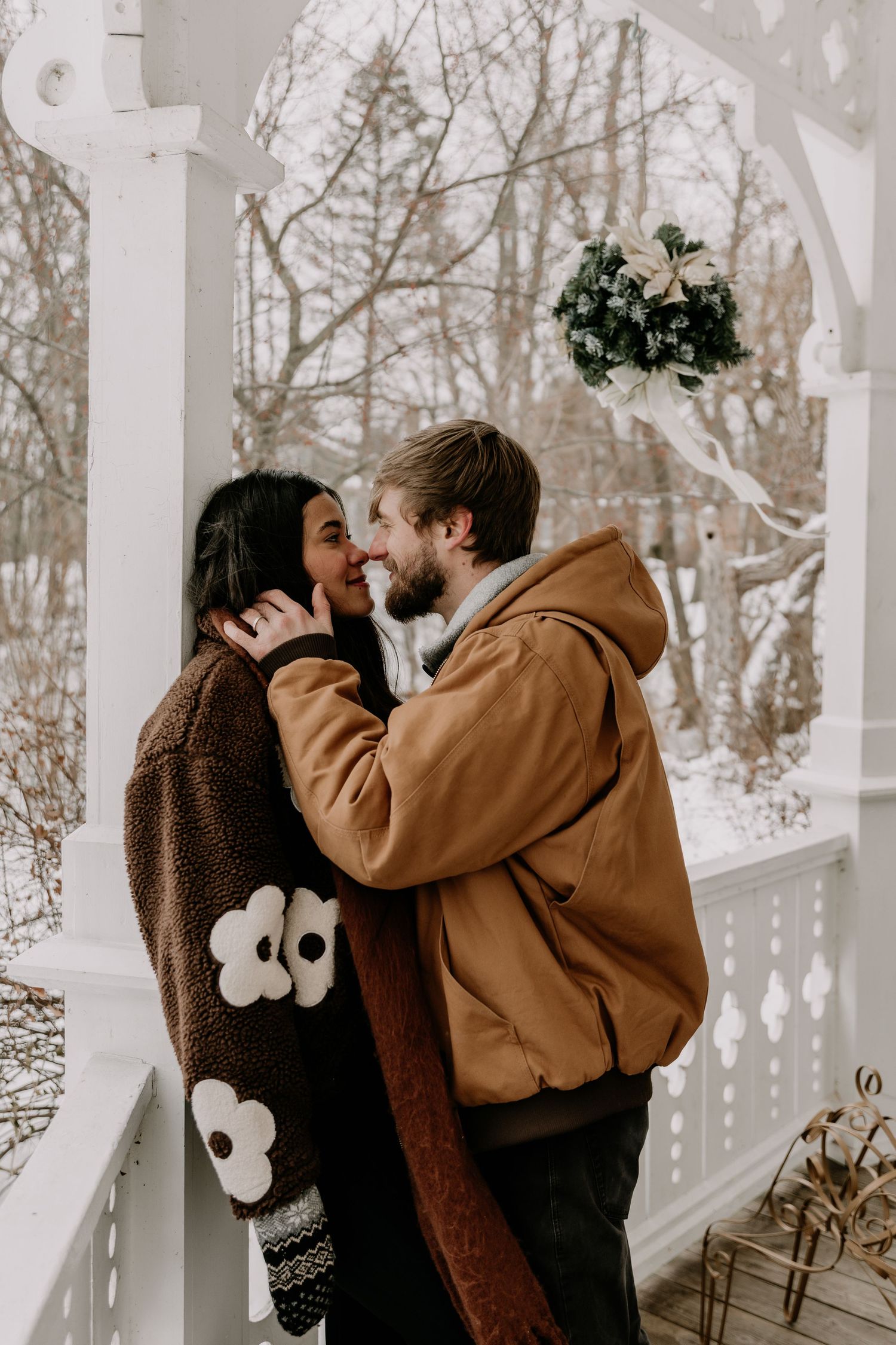 A romantic winter engagement photoshoot showing tender moments between a couple in a snowy wooded setting.