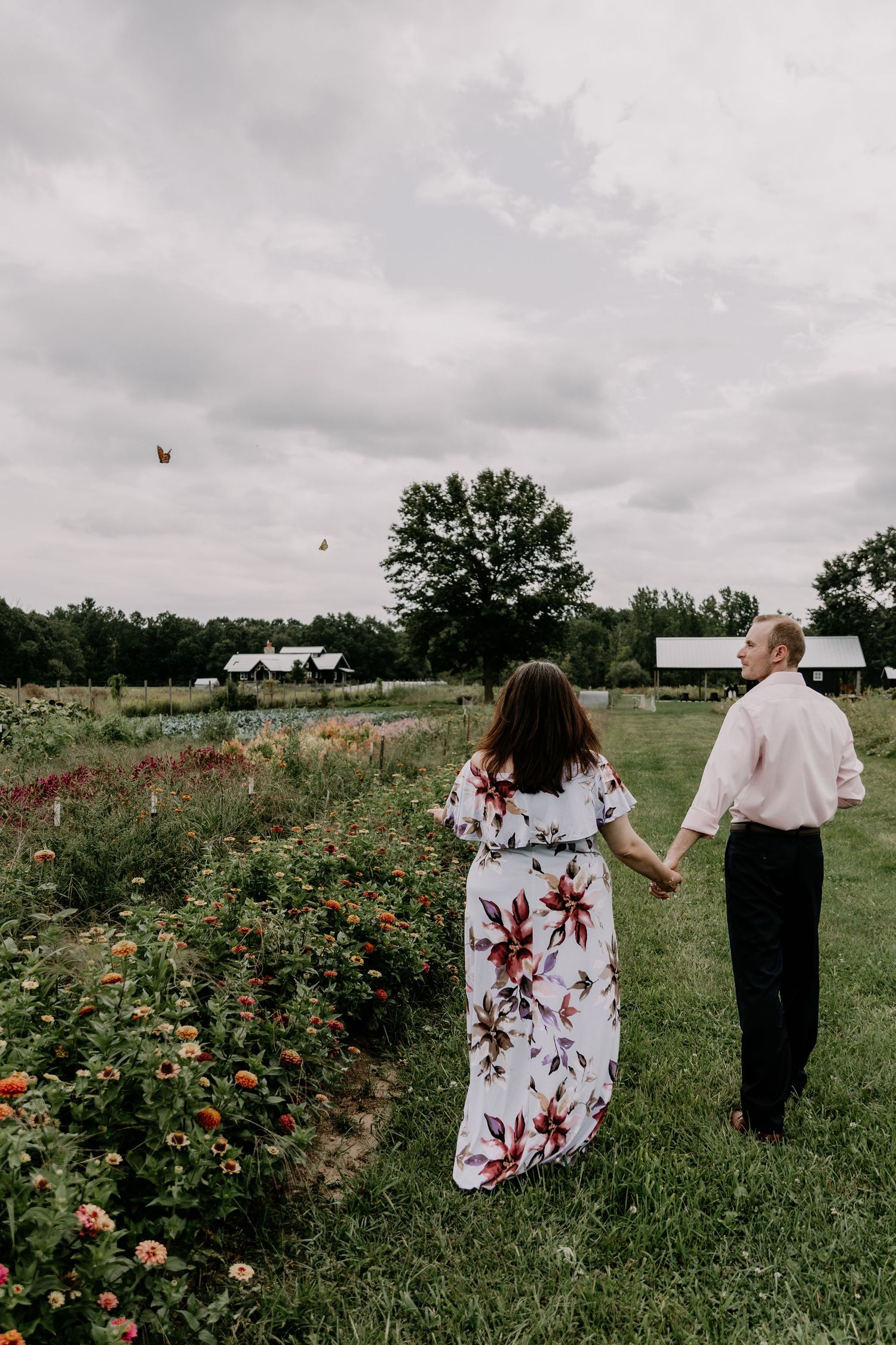 Two people walk together through a field of wildflowers and roses on a cloudy overcast day.