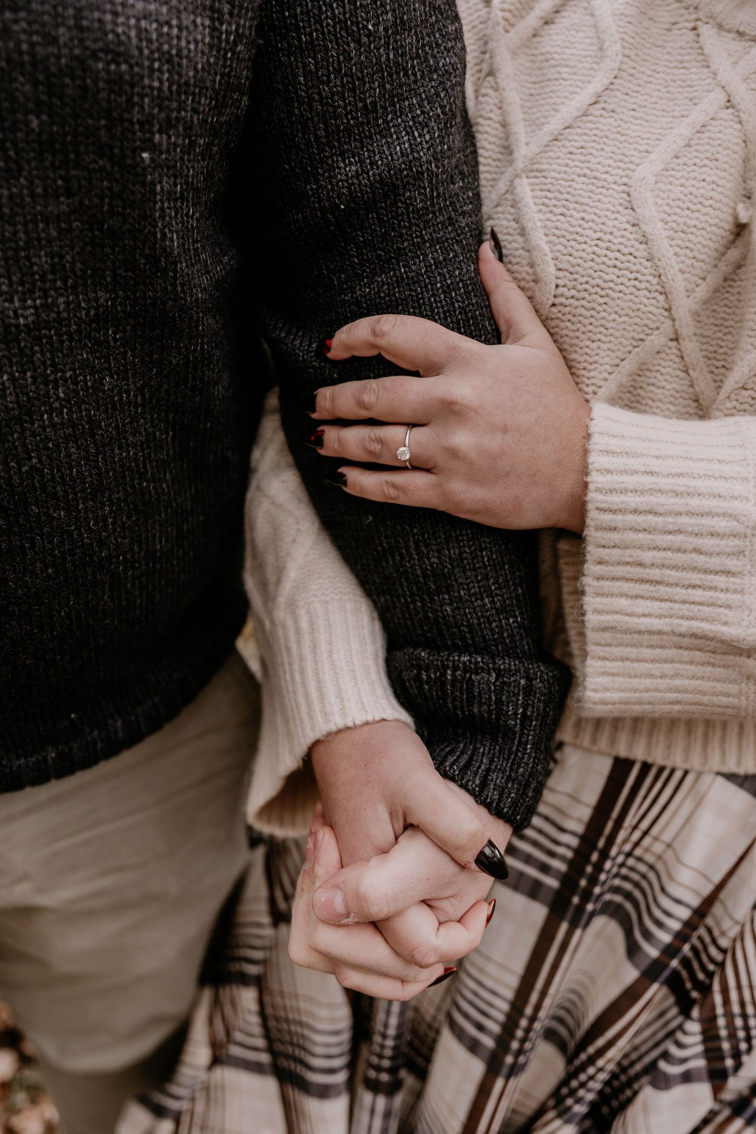 Close-up series of hands holding each other while wearing contrasting black and cream knit sweaters.