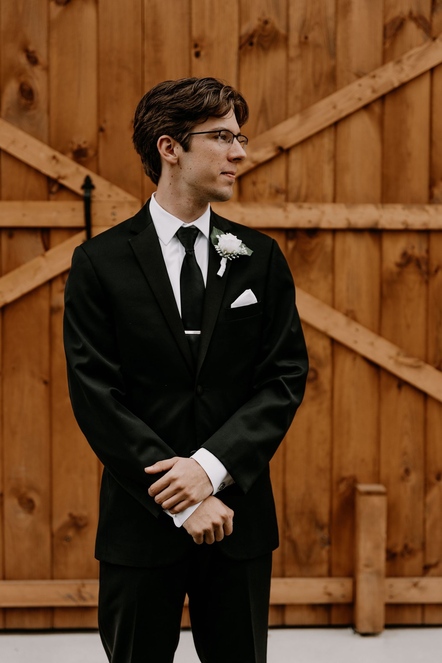 Formal attire details showing black suit jackets and ties against wooden paneling.