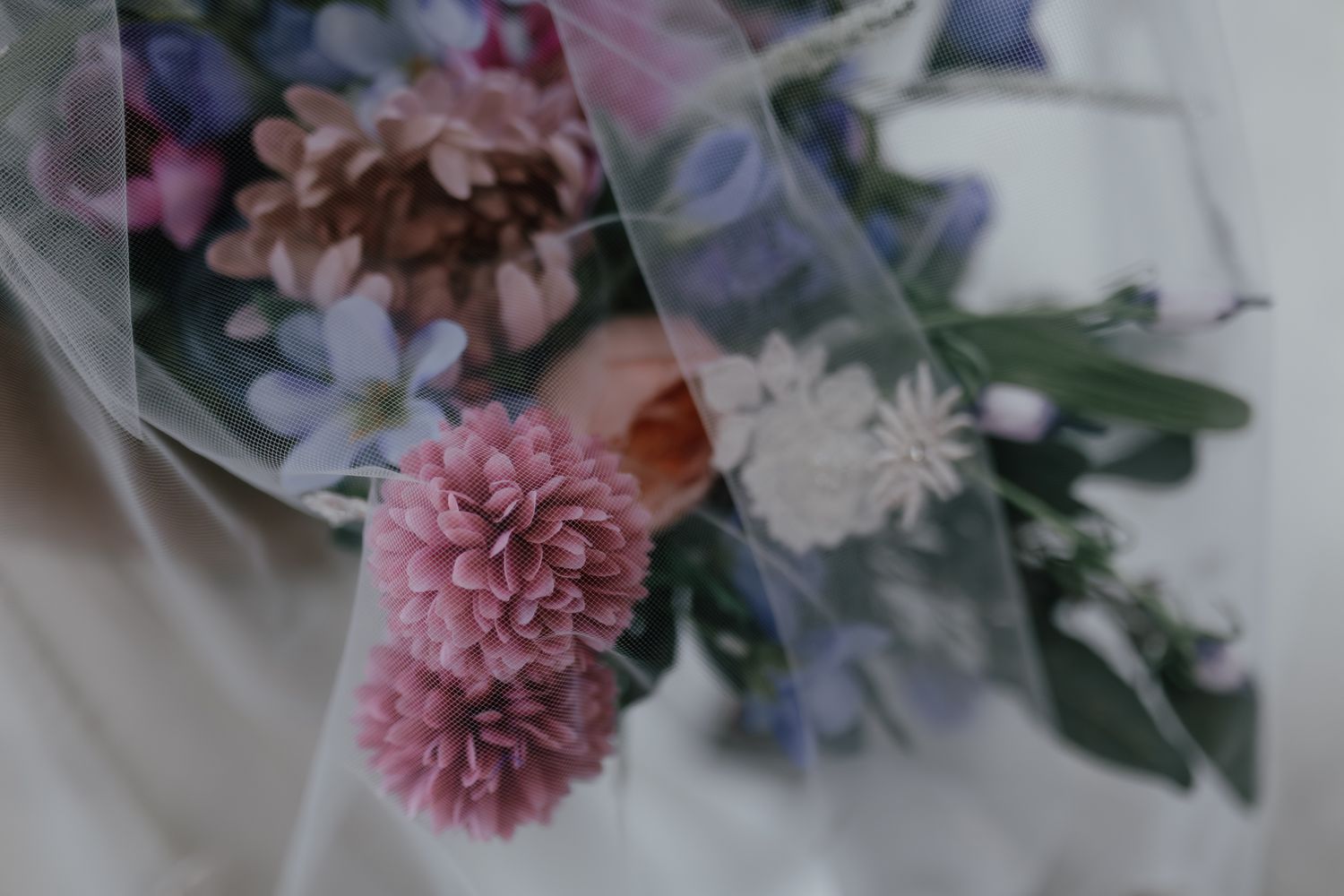 Soft focus close-up of pink and purple wedding bouquet flowers with delicate petals.