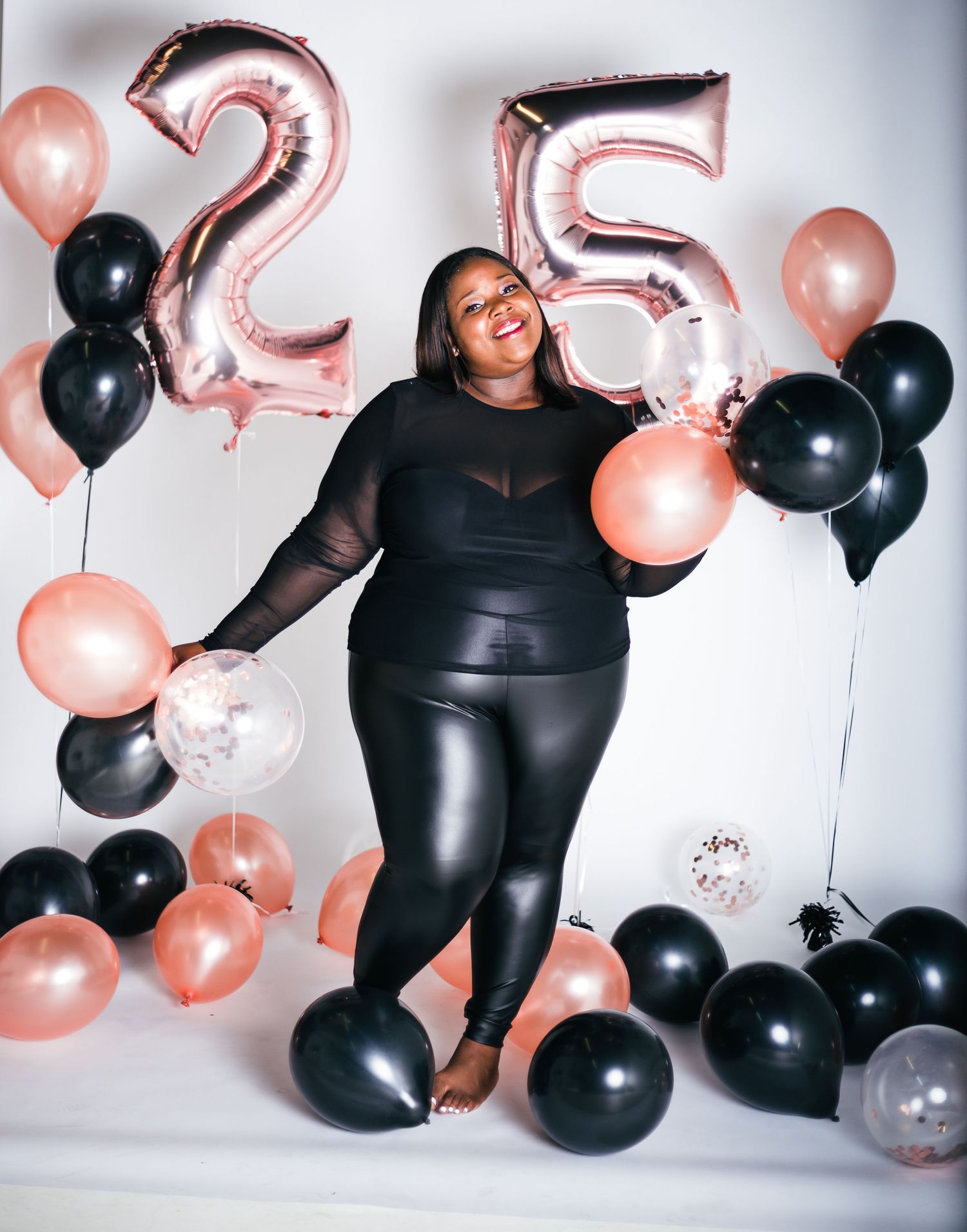 Studio photoshoot featuring black and rose gold balloon decorations.