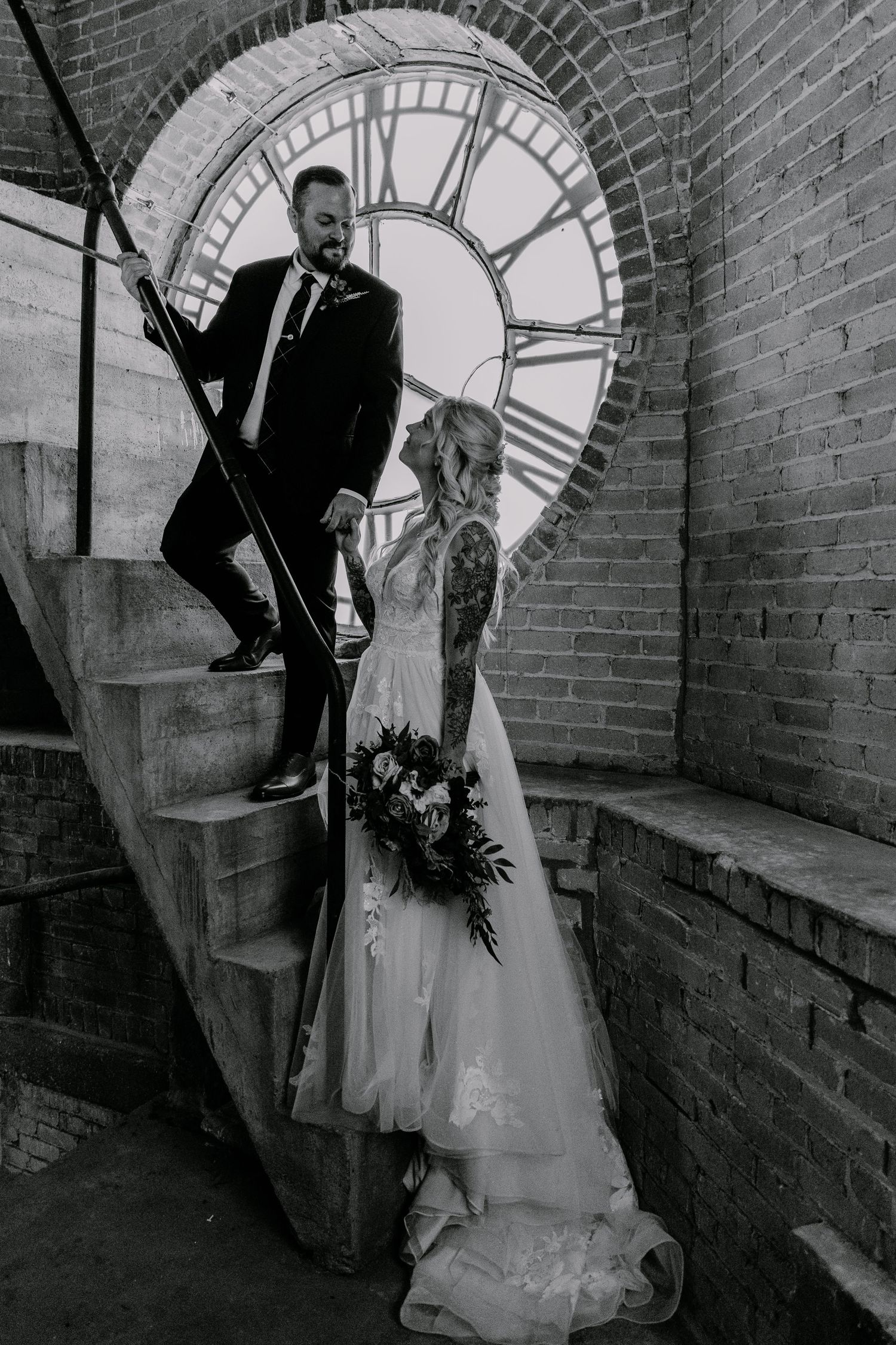 Black and white wedding photos against brick wall with large clock face showing romantic poses in vintage style.