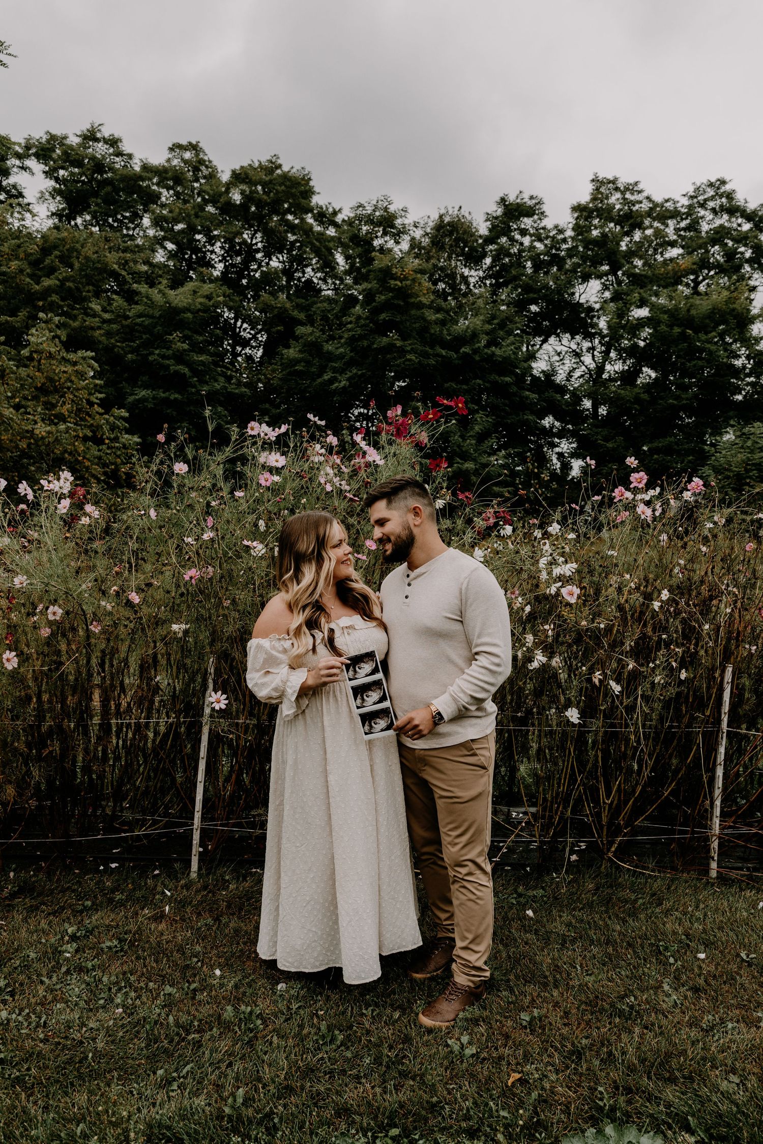 A couple shares tender moments among blooming wildflowers in a natural outdoor setting.