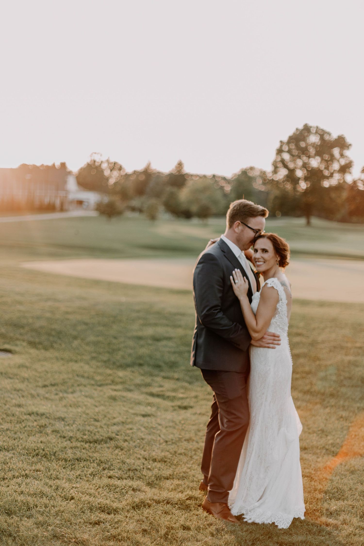 Newlyweds share an intimate moment during golden hour on their wedding day in an outdoor setting.