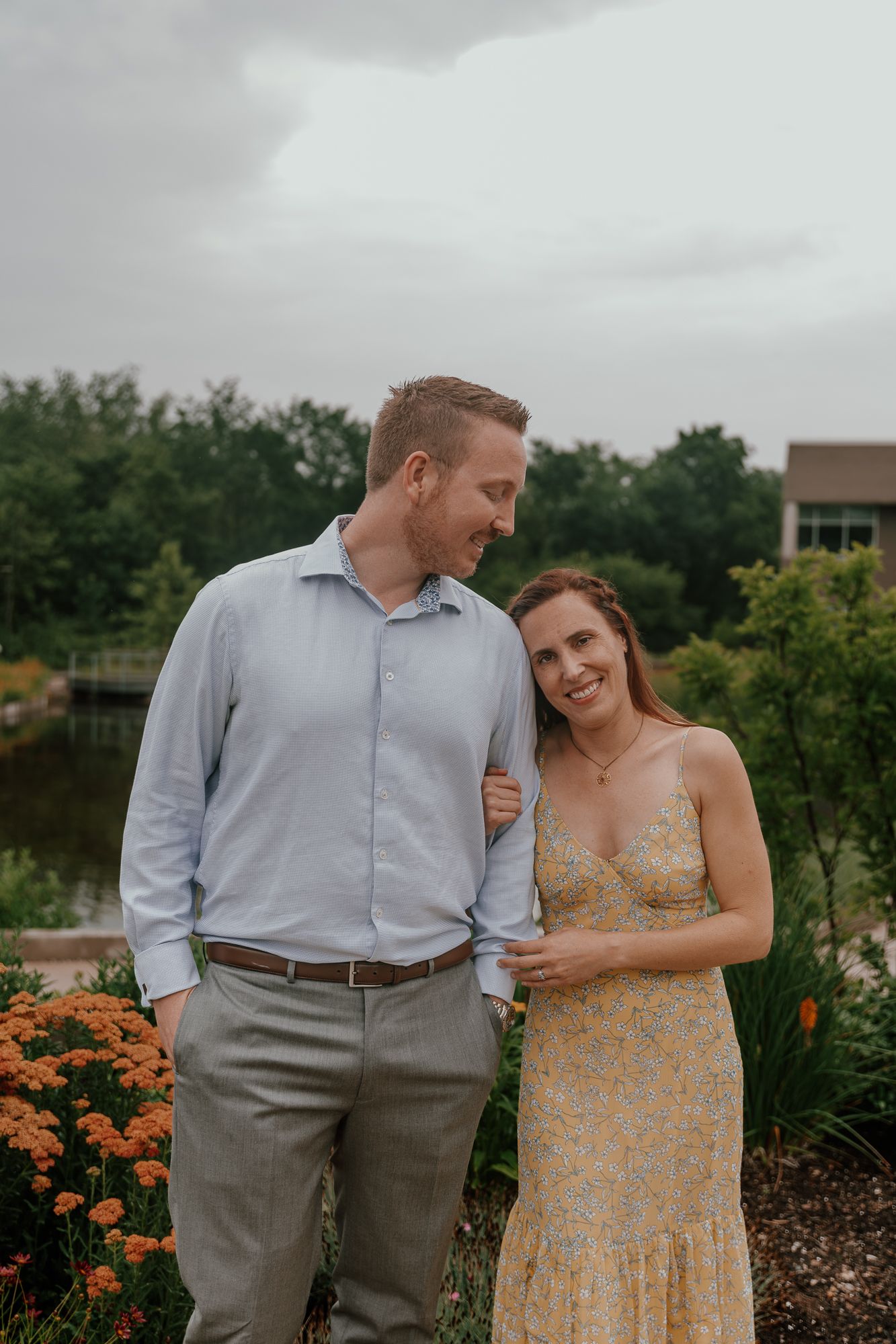 A couple shares a loving glance while standing in a garden with orange flowers.