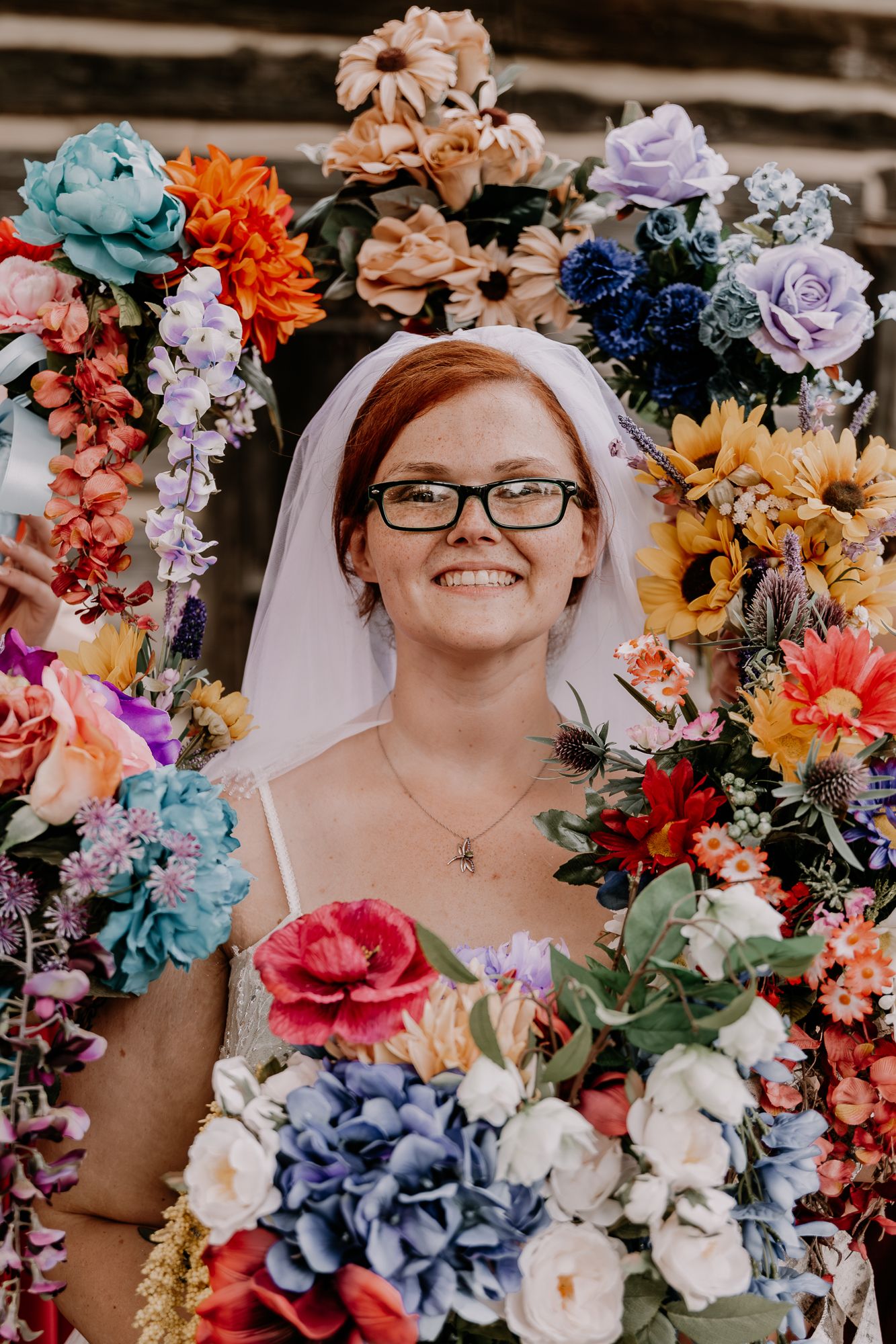 Colorful floral arrangement featuring blue, orange, pink and purple flowers with greenery.