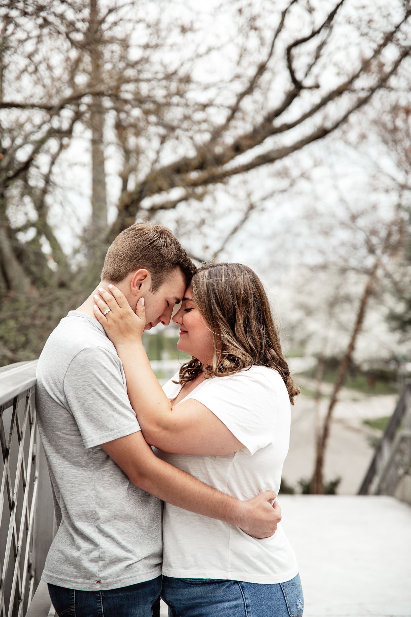 Intimate moment between couple embracing on wooden bridge during romantic photoshoot.