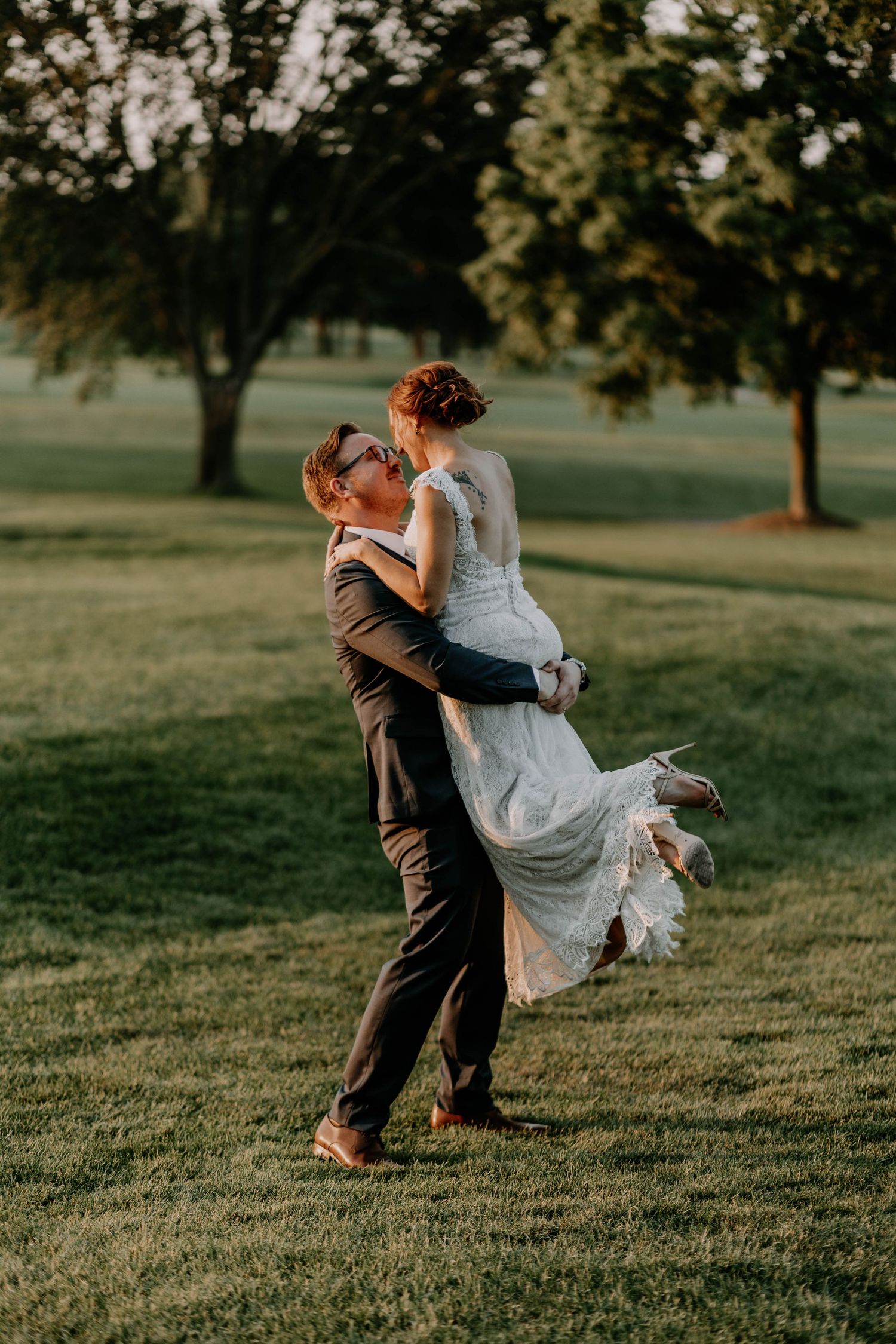 Romantic sunset dance scene with couple spinning on grassy lawn during wedding photoshoot.