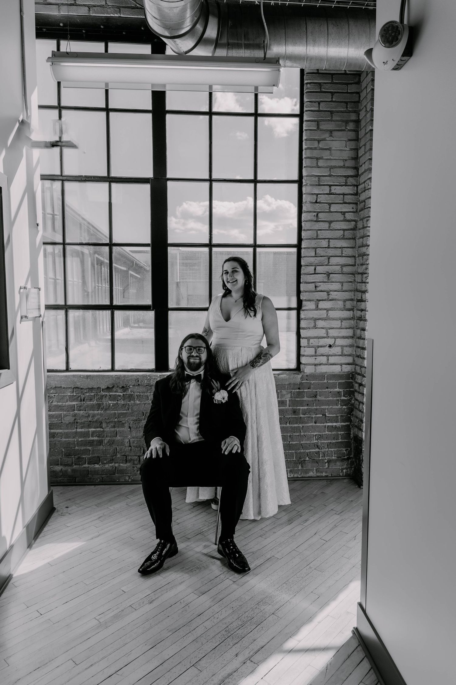 Artistic black and white portrait of couple in wedding attire in industrial setting.