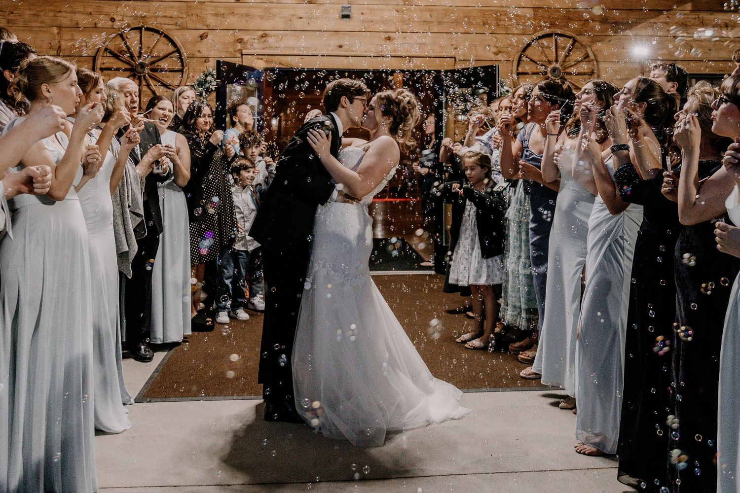 Wedding party celebrating at a rustic wooden barn venue with bubbles and festive atmosphere.