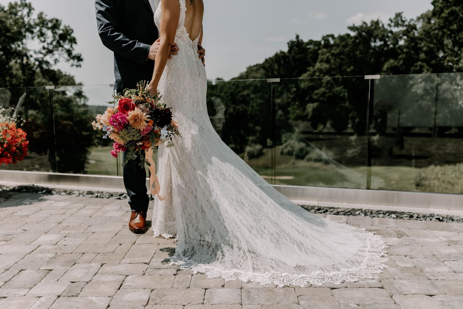 Close-up of bride's lace wedding dress train on stone patio during outdoor wedding portraits.